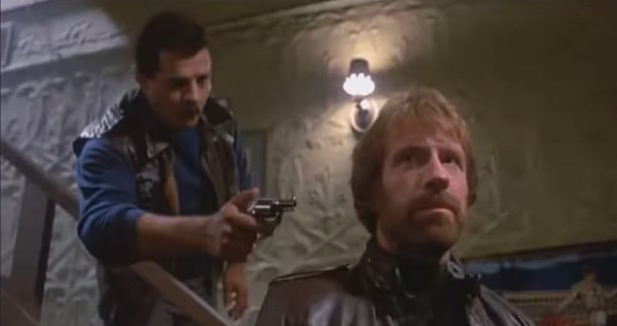 En Código de Silencio (1985), Norris interpretó al Sargento Eddie Cusack enfrentado al cartel colombiano Camacho en las calles de Chicago. La crítica la consideró su mejor actuación y lo comparó con John Wayne.- crédito fotograma de En Código de Silencio