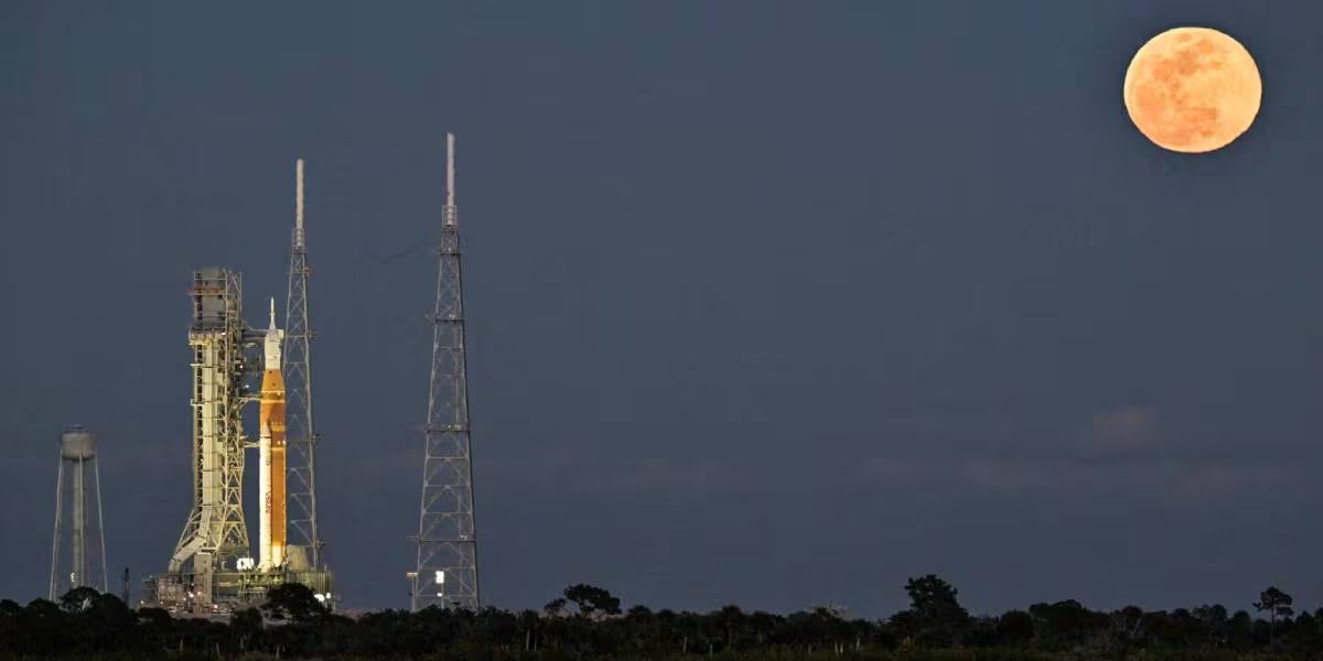 El cohete del programa Artemis se alza majestuosamente bajo una luna llena, preparándose para futuras misiones tripuladas como Artemis II, marcando el regreso de la humanidad a la exploración lunar. (Reuters)