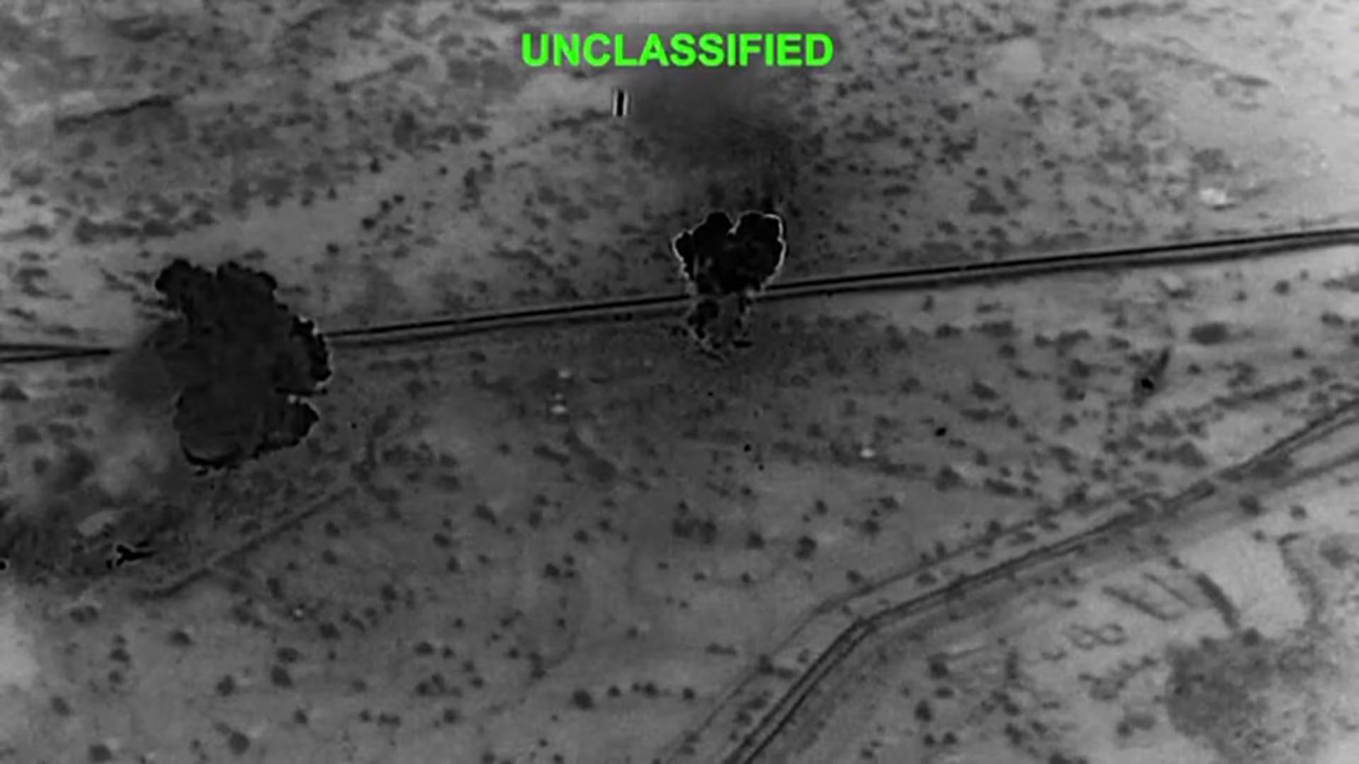 Captura de pantalla en monocromo que muestra el ataque de Estados Unidos contra la isla iraní de Kharg, donde se aprecian dos grandes explosiones en la superficie. (Captura de video)