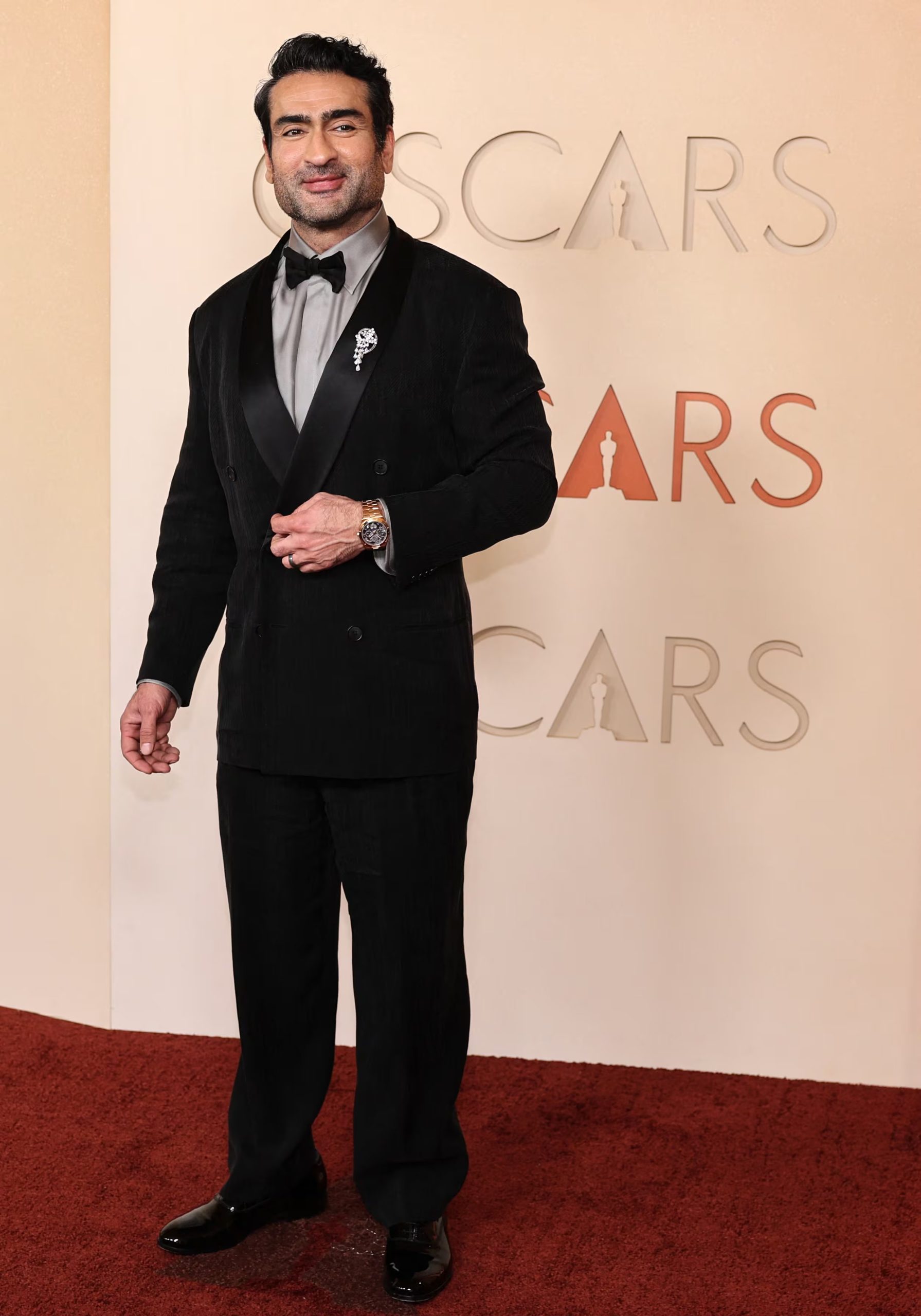 Kumail Nanjiani llevó un broche plateado en la solapa y un reloj metálico en la muñeca izquierda