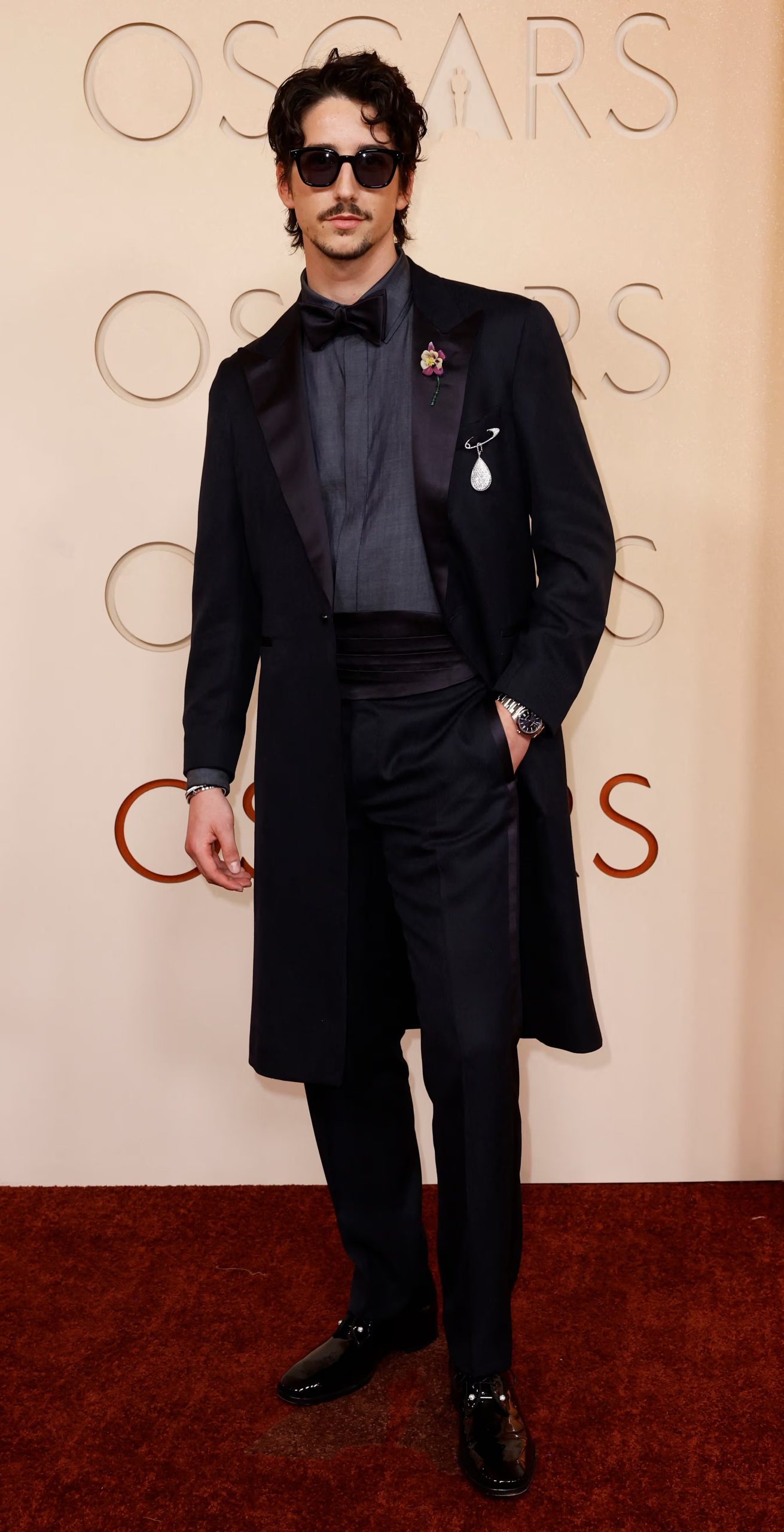 Milo Manheim añadió broches decorativos en la solapa, incluyendo una flor y un adorno brillante en forma de gota