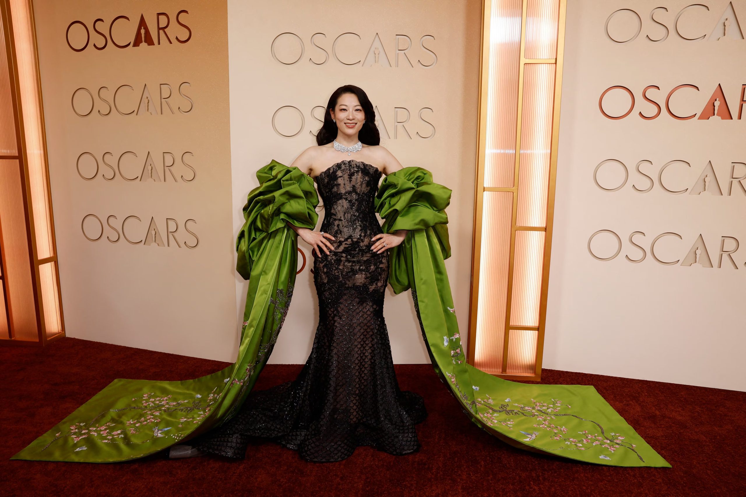 El look de Arden Cho resaltó con mangas de satén verde y bordados florales, en contraste con la silueta negra ajustada 