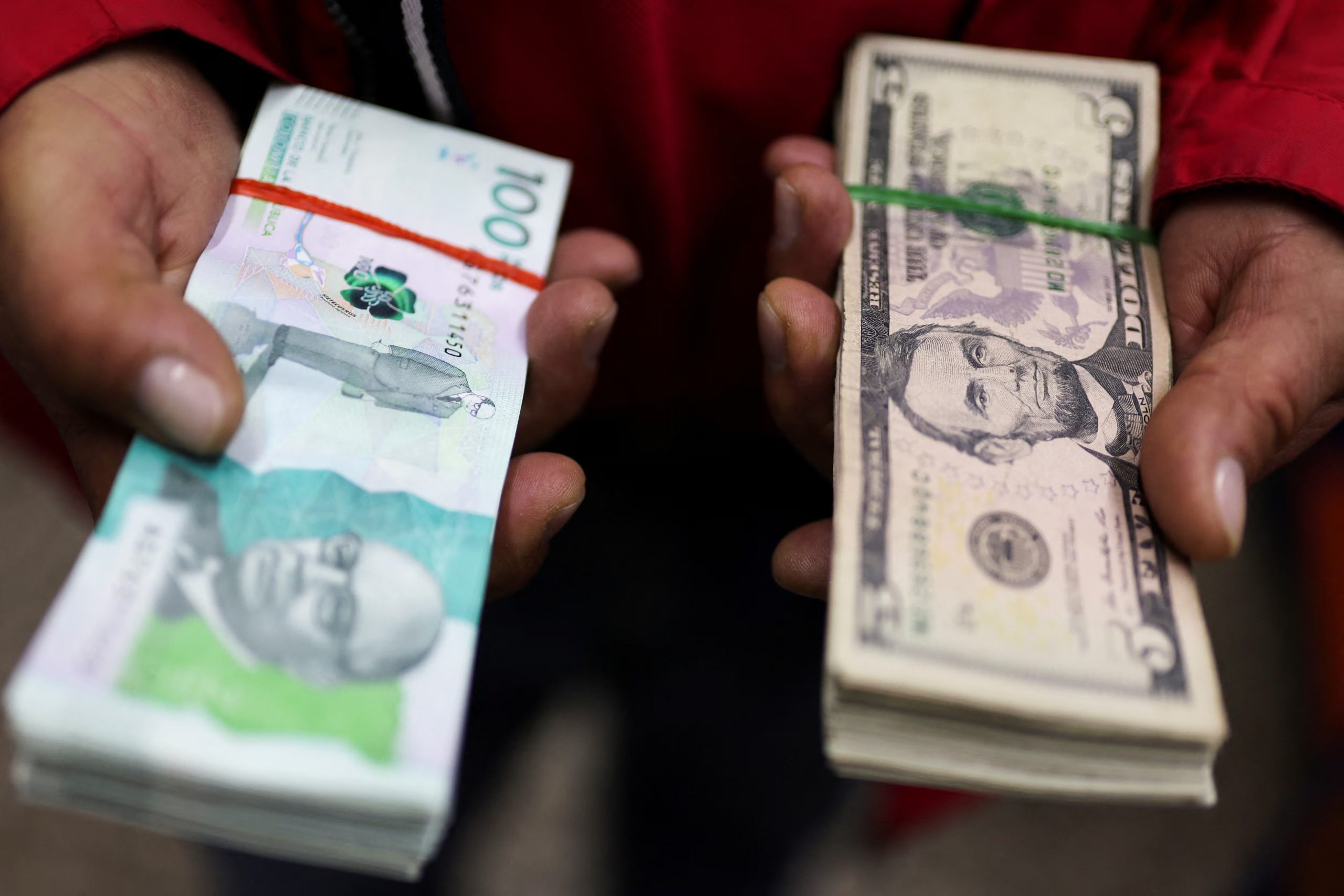 FOTO DE ARCHIVO-Un empleado muestra un billete de cien mil pesos colombianos y otro de cinco dólares estadounidenses en una casa de cambio, en Bogotá, Colombia. 27 de enero de 2025. REUTERS/Luisa González