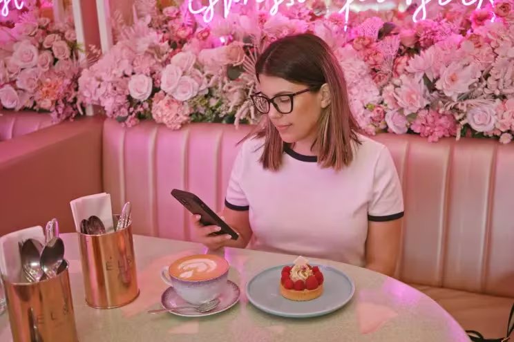 Una comensal disfruta de un café y postre en un restaurante de ambiente sensorial, donde la experiencia se centra en el autocuidado y la calma.