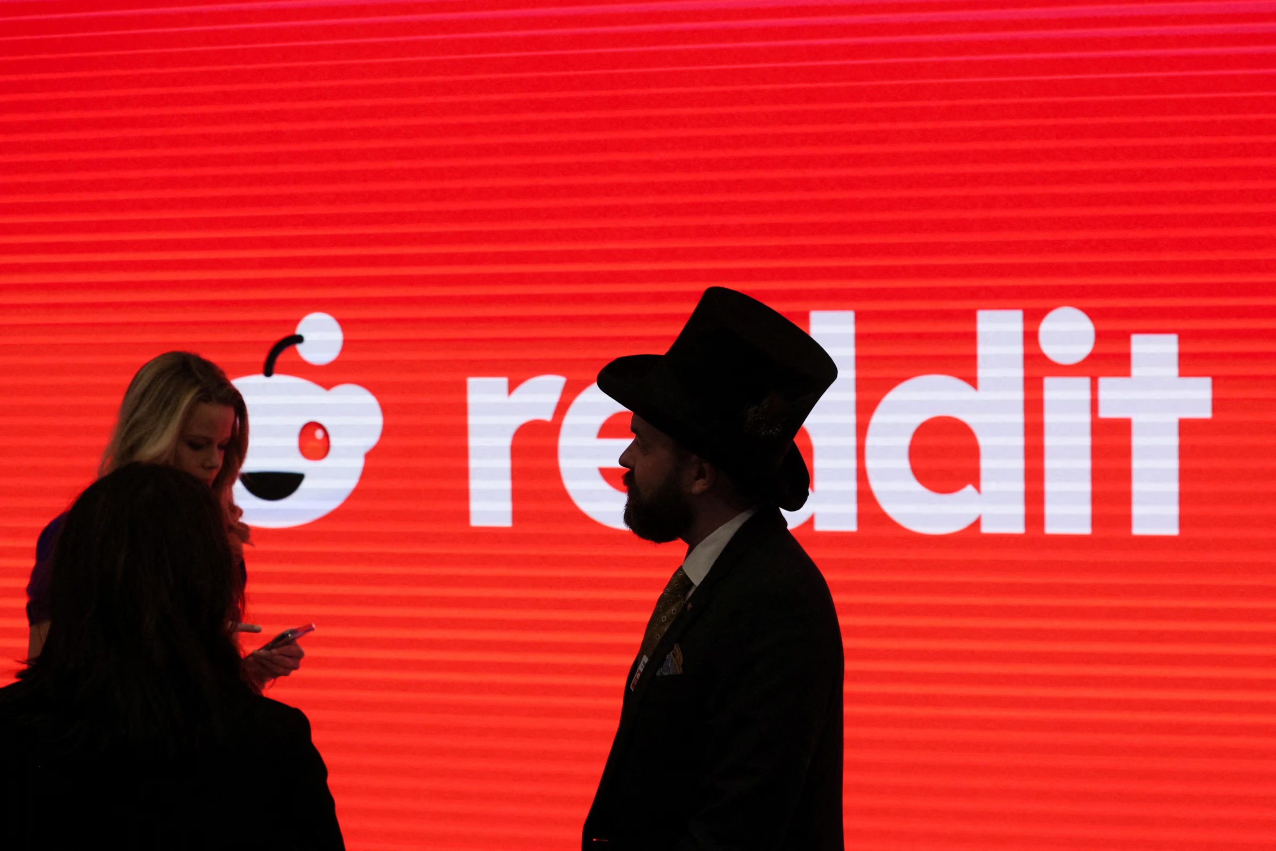 FILE PHOTO: People stand in front of Reddit's logo, at the New York Stock Exchange (NYSE) in New York City, U.S., March 21, 2024. REUTERS/Brendan McDermid/File Photo