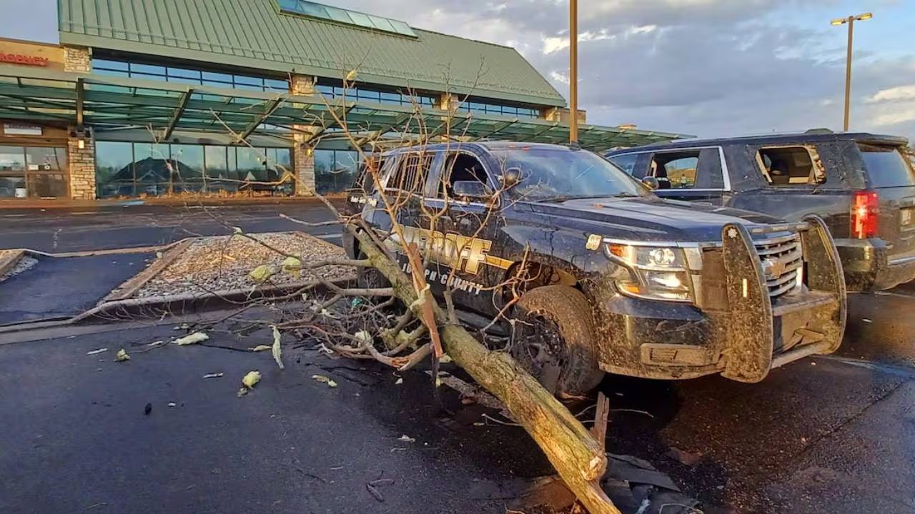 Dos vehículos presentan daños severos tras el impacto de un tornado, con ramas y escombros dispersos en el estacionamiento. (Reuters)
