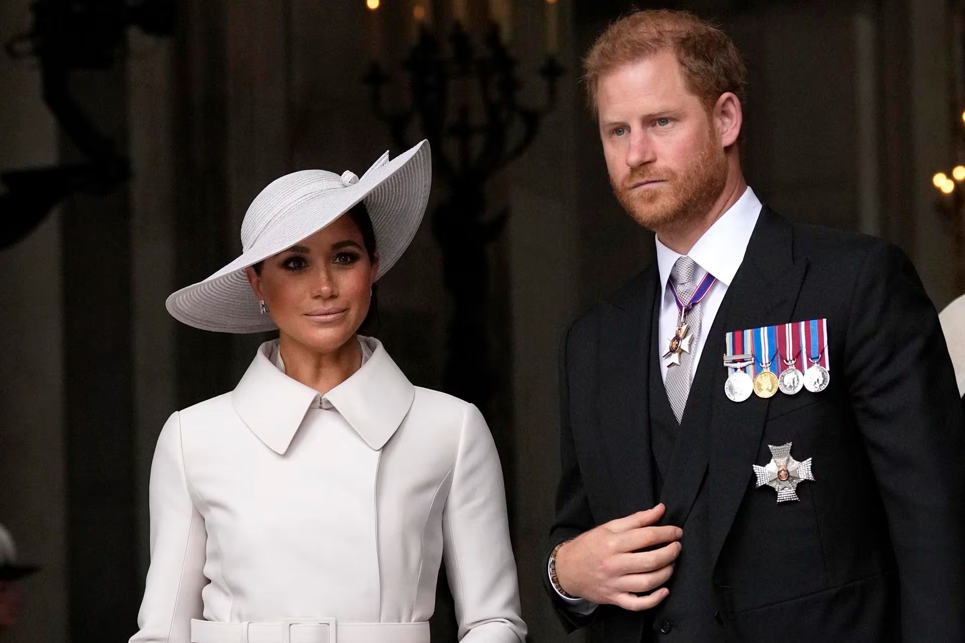 El sombrero blanco de ala ancha de Meghan Markle, elegido junto al príncipe Harry, completó un look monocromático y sofisticado, reafirmando su estilo propio en eventos oficiales (AP)