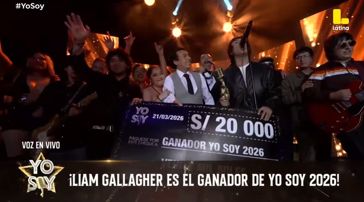 El imitador de Liam Gallagher celebra su victoria en Yo Soy 2026, sosteniendo el cheque de S/ 20,000 y el trofeo, rodeado de aplausos en el escenario. (Yo Soy)