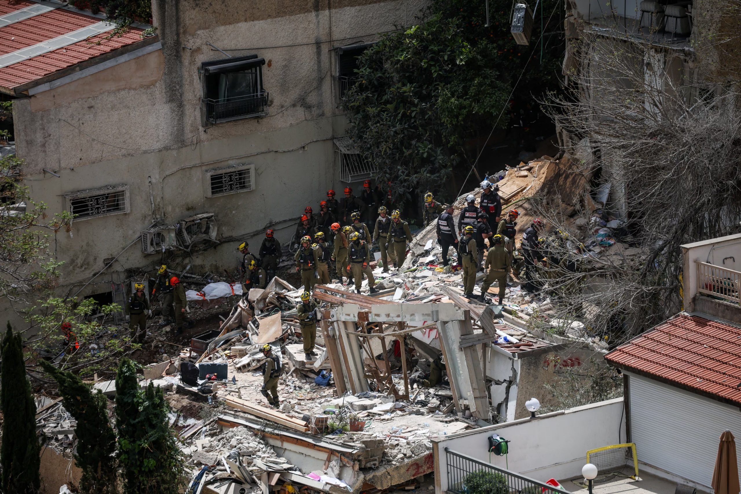 Personal de emergencia retira un cuerpo del sitio del impacto en Haifa. La operación de rescate se extendió por 18 horas hasta recuperar a las cuatro víctimas entre los escombros del edificio derrumbado. (REUTERS/Shir Torem)