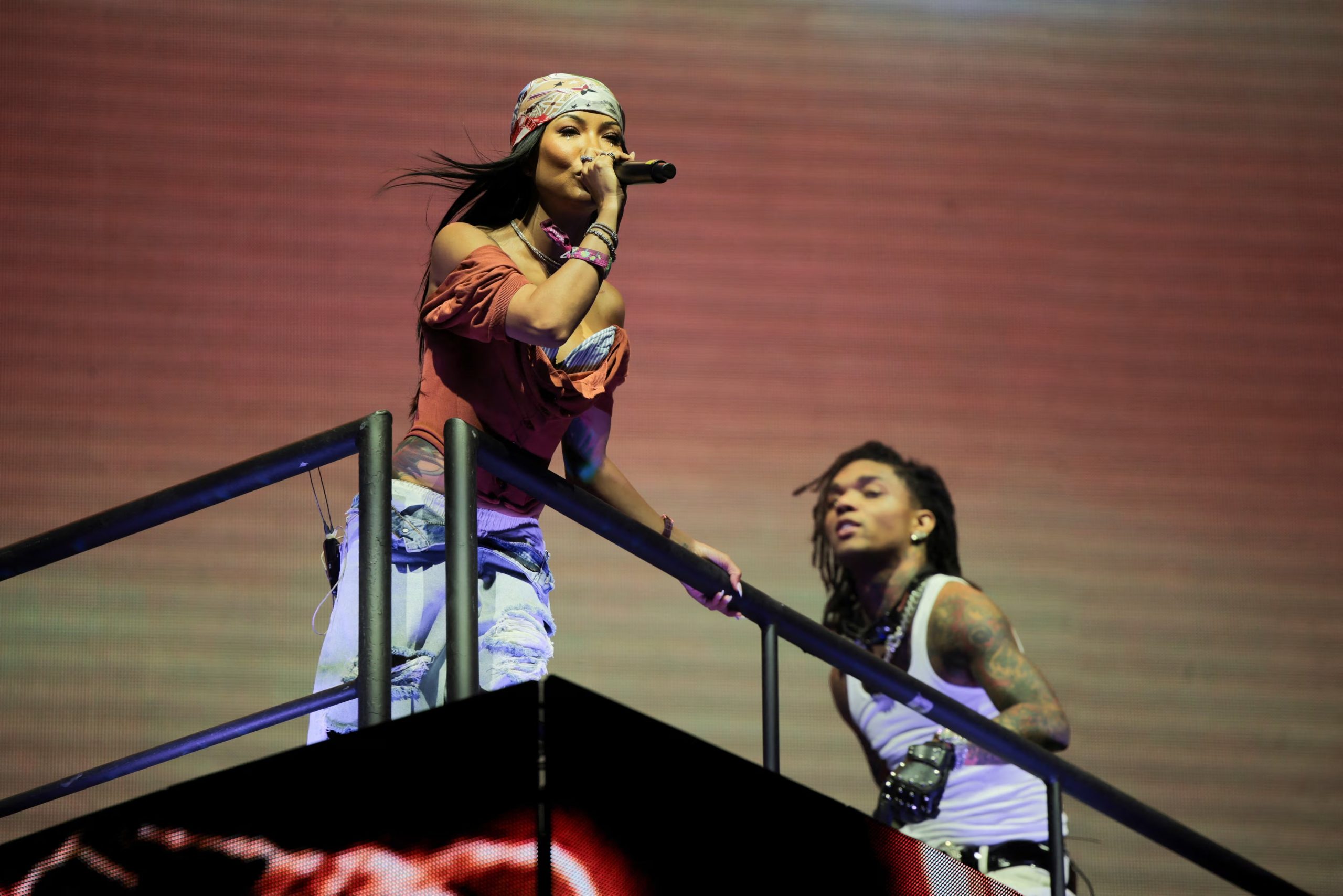 Jhene Aiko combinó un top marrón de manga caída con pantalón azul claro y pañuelo estampado, logrando un look boho chic ideal para el ambiente de Coachella (REUTERS/Daniel Cole)