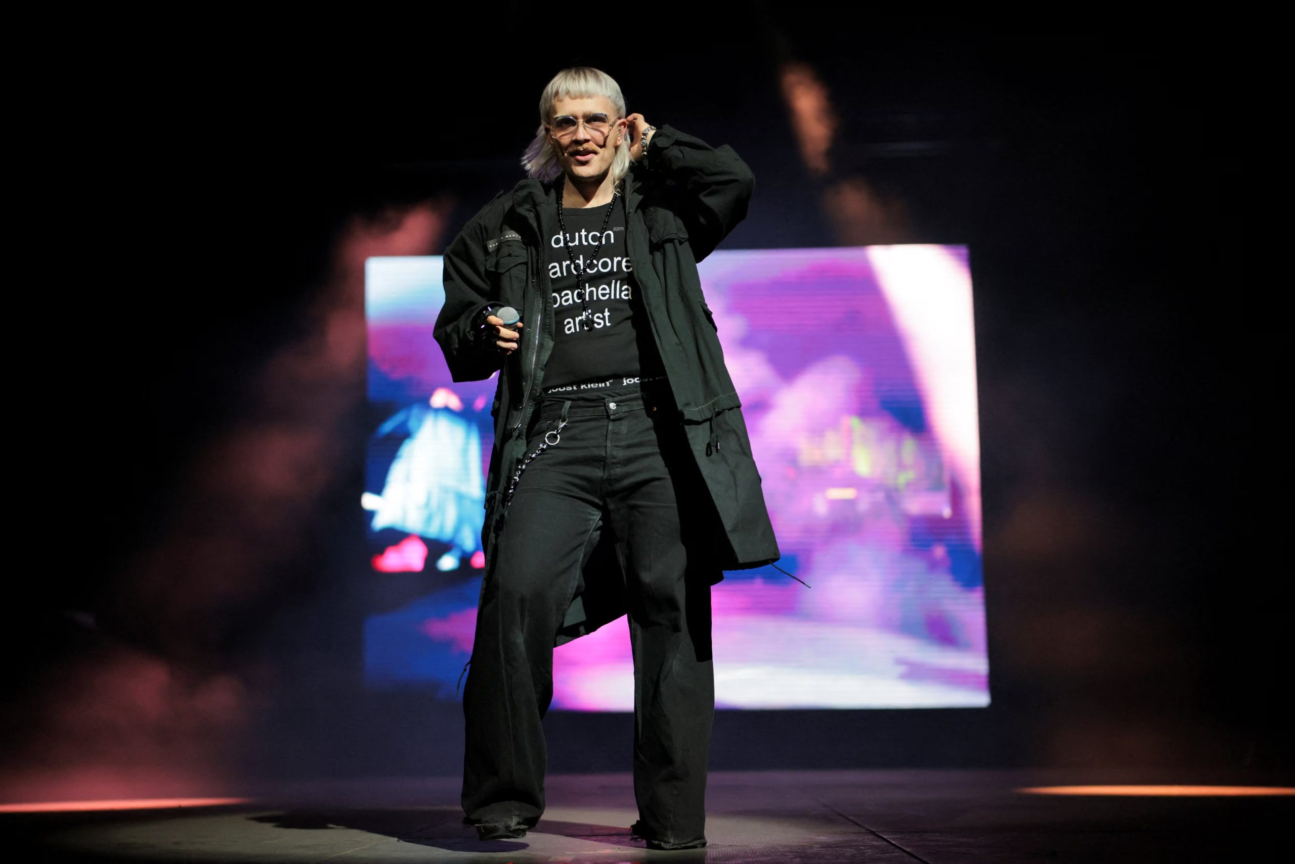 Joost apostó por la sobriedad con un abrigo negro oversize, camiseta con texto blanco y pantalón ancho, sumando anteojos de sol translúcidos y cadenas para un aire relajado y moderno (REUTERS/Daniel Cole)