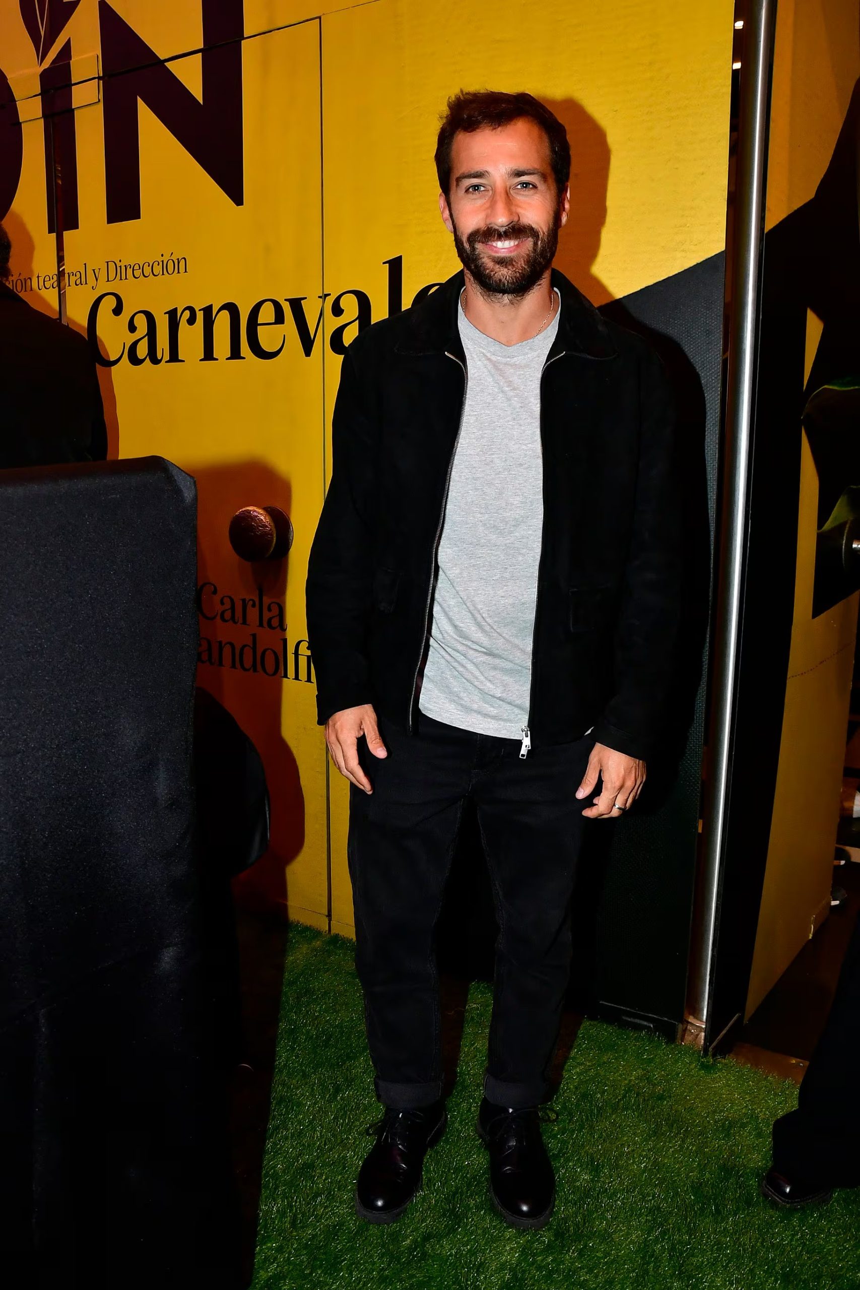 Nicolás Francella posa sonriente frente a un cartel amarillo durante la presentación de la obra teatral 'Desde el jardín', de pie sobre césped artificial. (RS Fotos)