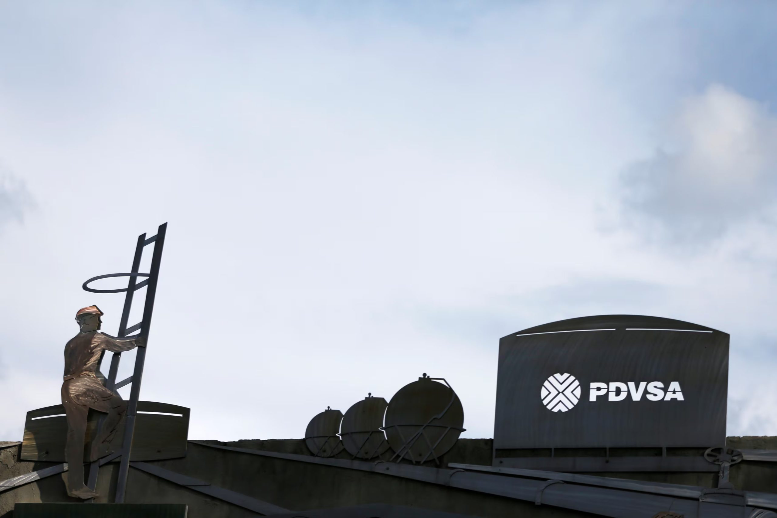 El logotipo de la petrolera venezolana PDVSA y un trabajador se ven en un edificio de la empresa (REUTERS/Carlos García Rawlins)