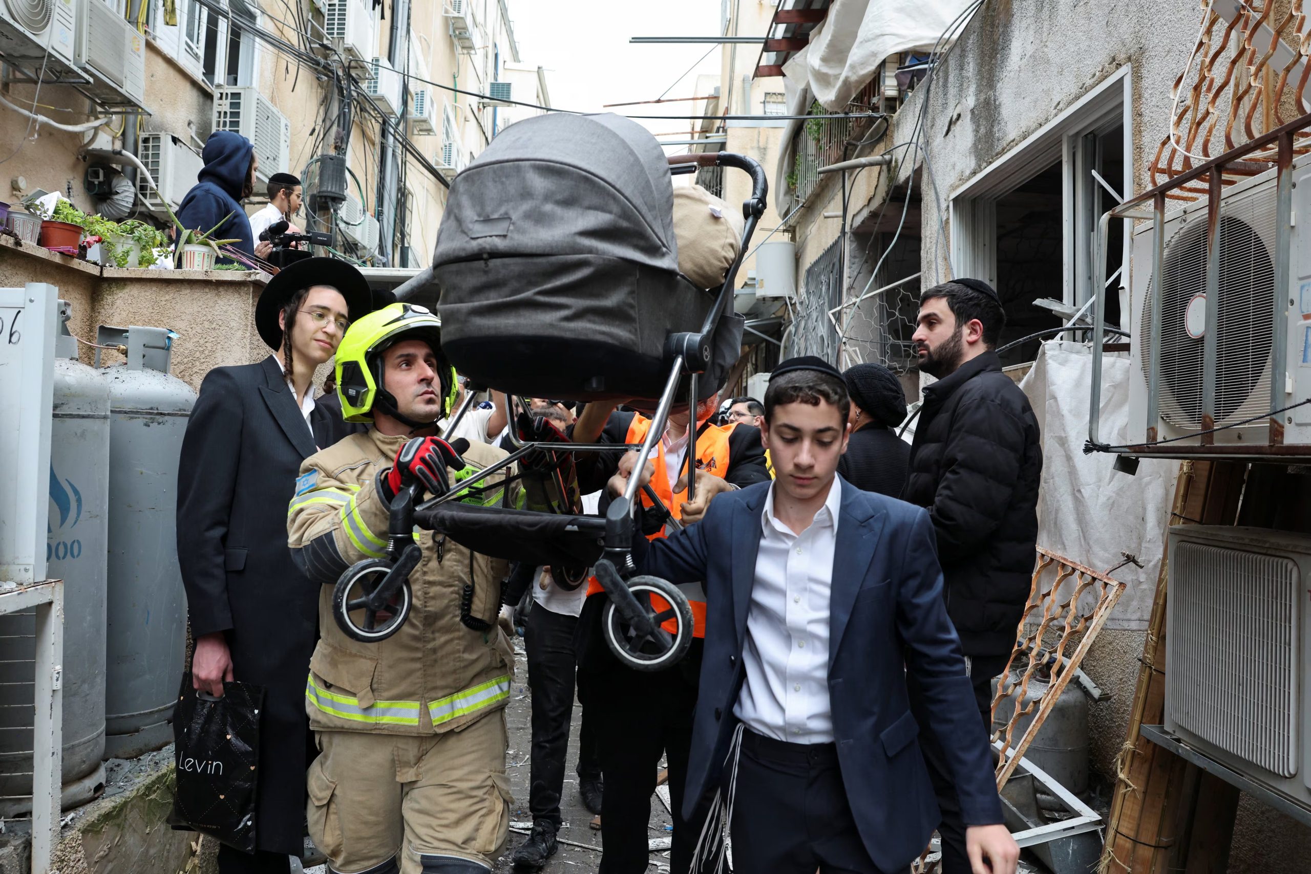 Personal de emergencia israelí transporta un cochecito de bebé en la zona del impacto, tras el lanzamiento de misiles iraníes contra Israel (REUTERS/Nir Elias)