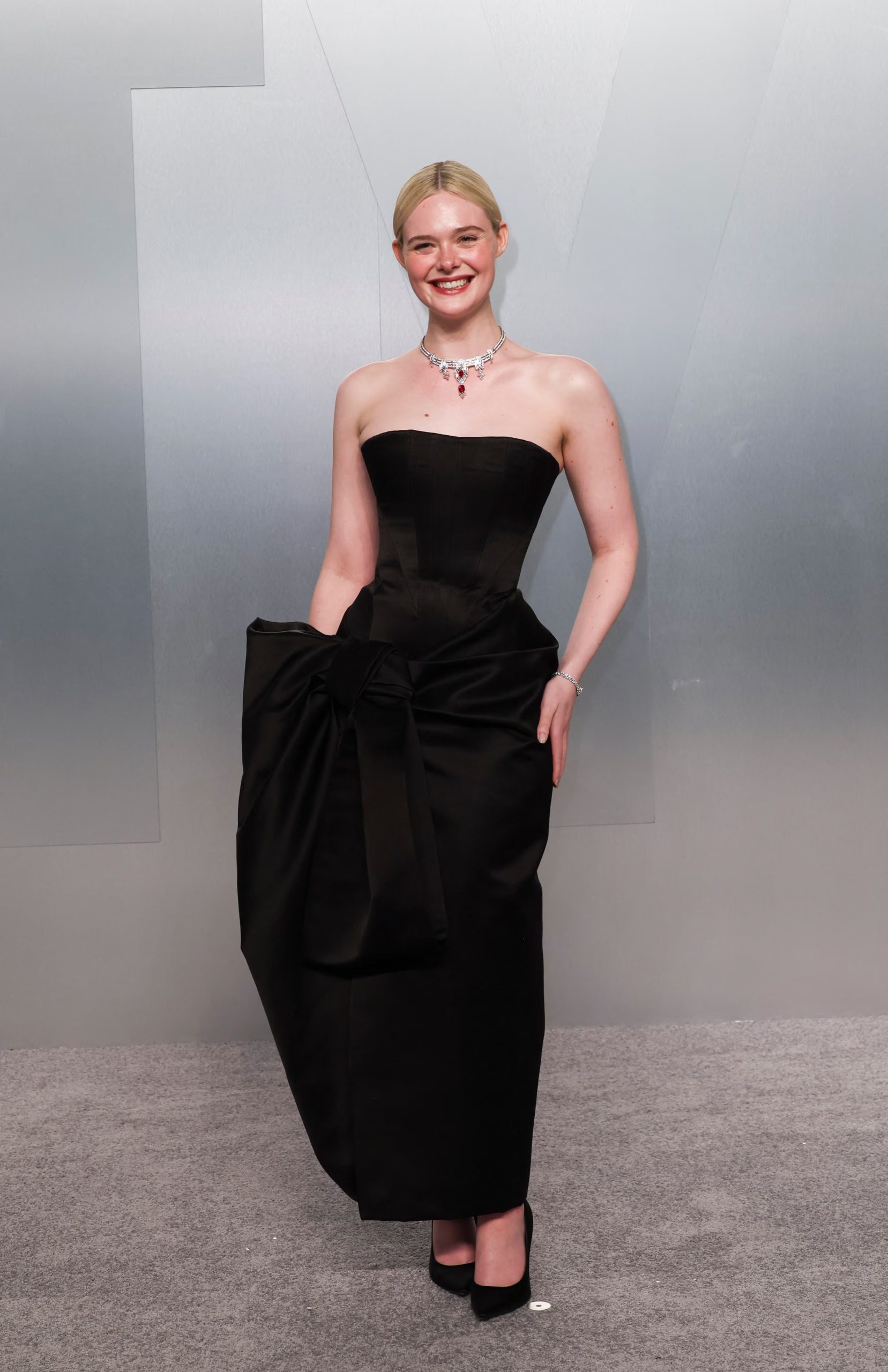 El vestido negro con lazo azul resalta la silueta estructurada de Elle Fanning, combinando un corsé sin tirantes y texturas satinadas para lograr una presencia poderosa y sofisticada en la alfombra roja (REUTERS/Danny Moloshok)