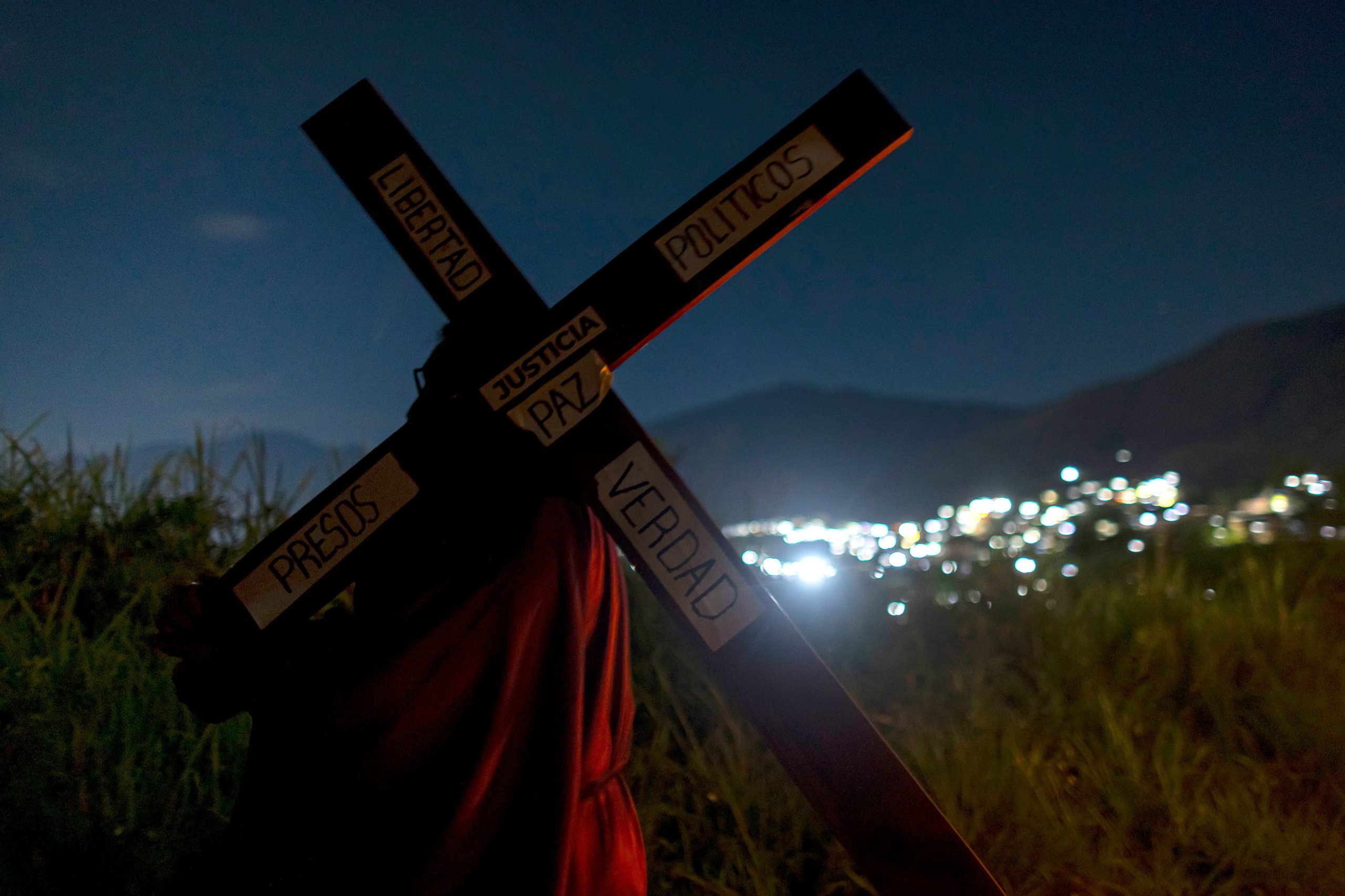 Un hombre, familiar de un preso político, carga una cruz durante un viacrusis este miércoles, en las afueras del Rodeo I (EFE/Miguel Gutiérrez)