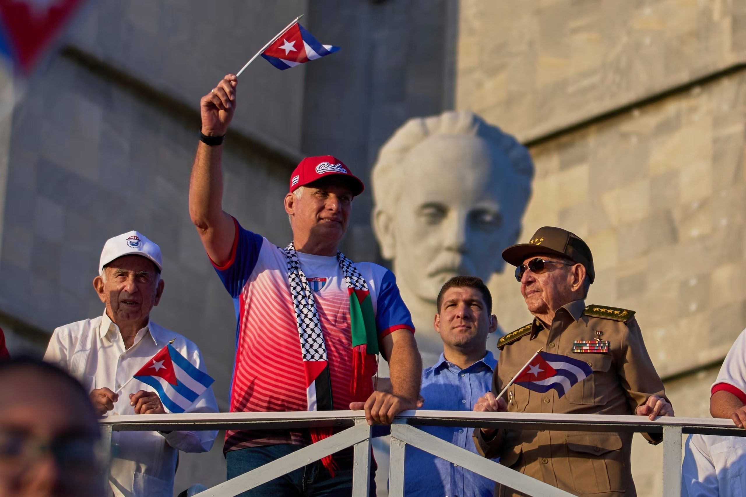 El dictador de Cuba Miguel Diaz-Canel ondea una bandera cubana mientras mira el desfile del Día del Trabajo junto a Raúl Castro, segundo de derecha a izquierda, y Raul Guillermo Rodríguez Castro, nieto de Raúl Castro, en la Plaza de la Revolución en La Habana, el 1 de mayo de 2025 (AP/Ramon Espinosa)