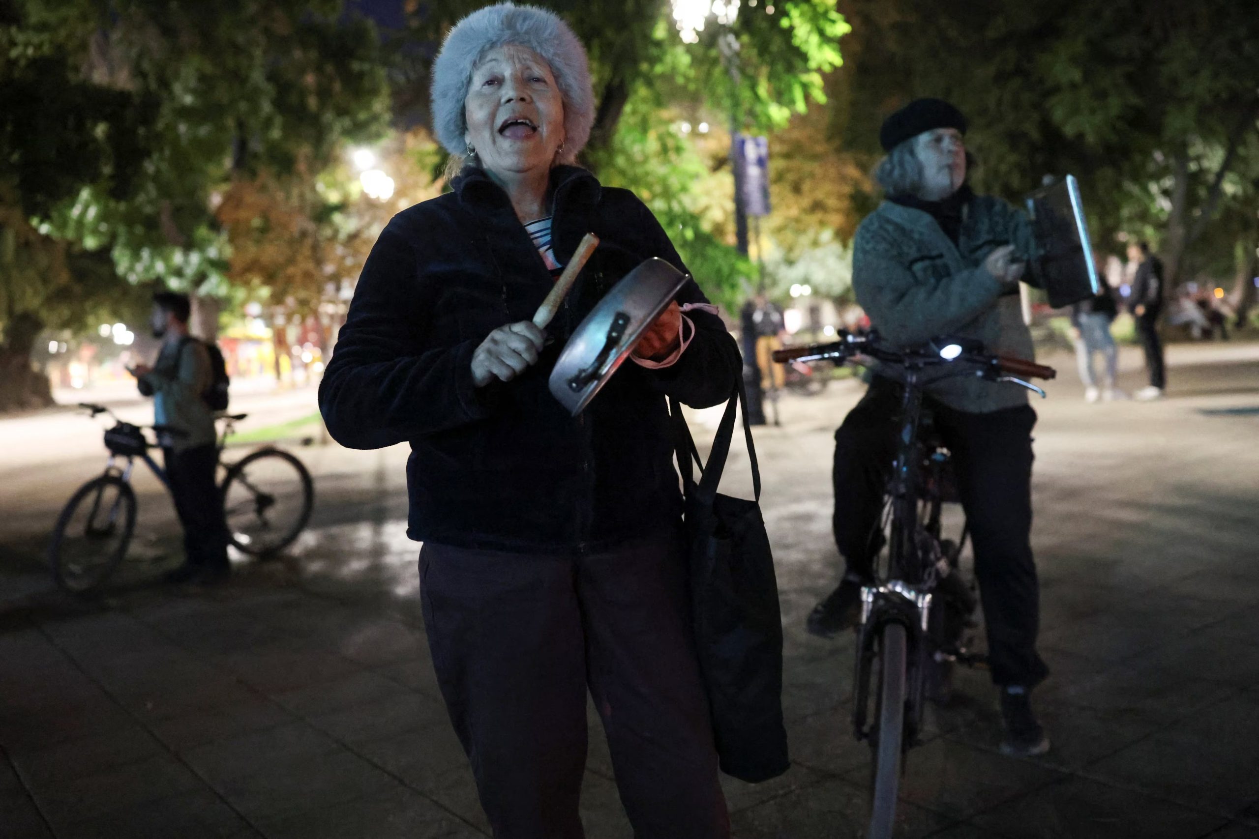 Una mujer protesta contra el gobierno golpeando un utensilio mientras el presidente de Chile, José Antonio Kast, realiza anuncios económicos en una transmisión nacional, en Santiago de Chile, el 15 de abril de 2026 (REUTERS/Pablo Sanhueza)