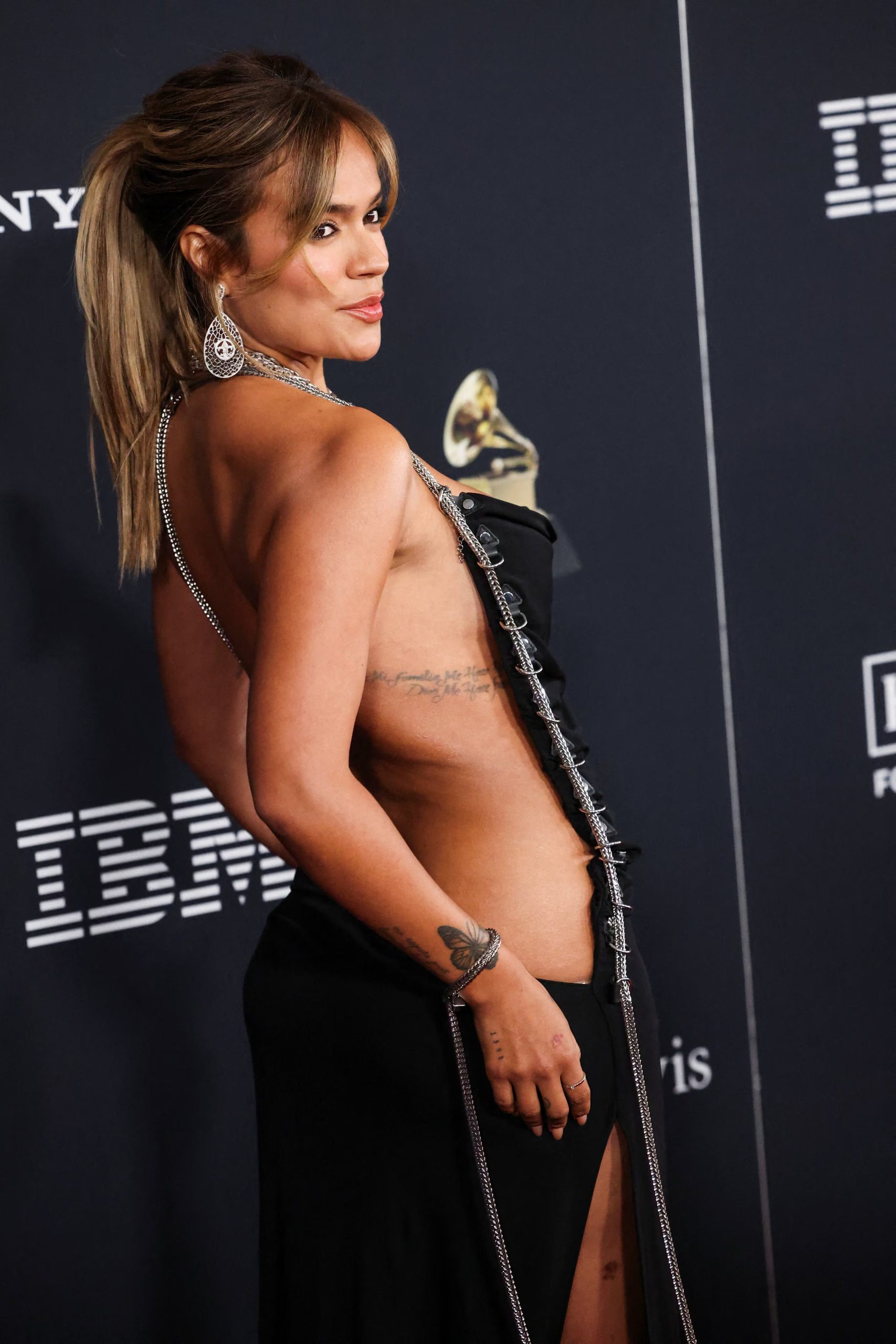 El vestido negro con corte lateral, cadenas plateadas y espalda descubierta resalta la sensualidad y el estilo atrevido de Karol G en la Pre-Grammy Gala (REUTERS/Mario Anzuoni)