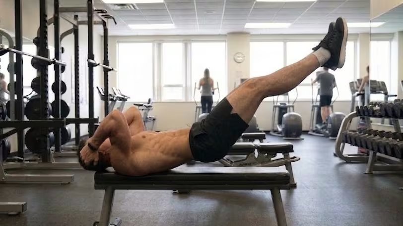 La variante inicial del Dragon Flag permite a los principiantes desarrollar fuerza abdominal elevando solo piernas y cadera para una mayor adaptación (Imagen Ilustrativa Infobae)