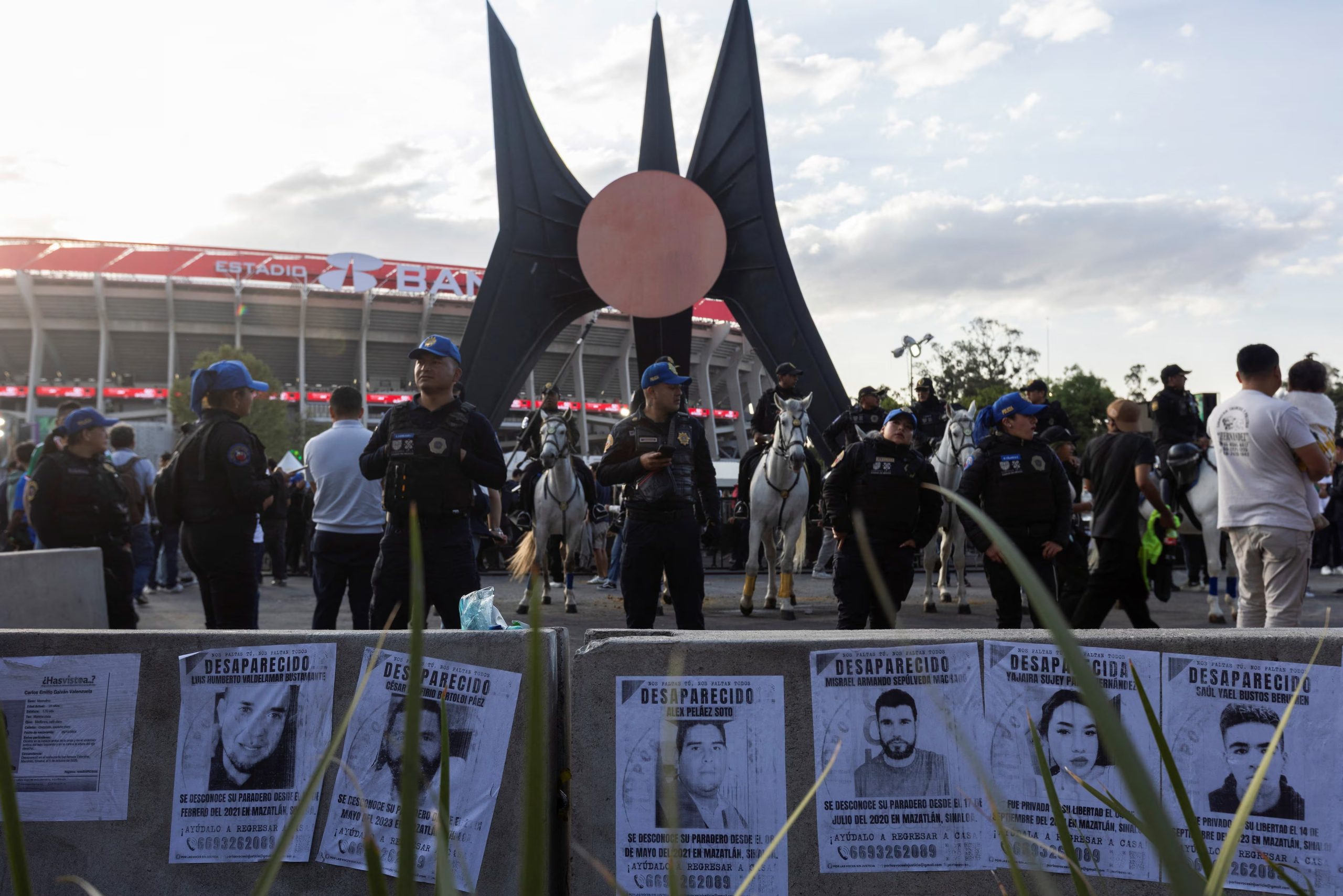 Police officers, including mounted police, stand guard near posters of missing people as relatives of victims of forced disappearance protest outside Azteca Stadium, officially renamed Estadio Banorte, on the day of a friendly match between the national teams of Mexico and Portugal held to mark the stadium’s inauguration, as Mexico prepares for the 2026 FIFA World Cup co-hosted by the United States, Canada and Mexico, in Mexico City, Mexico, March 28, 2026. REUTERS/Quetzalli Nicte-Ha