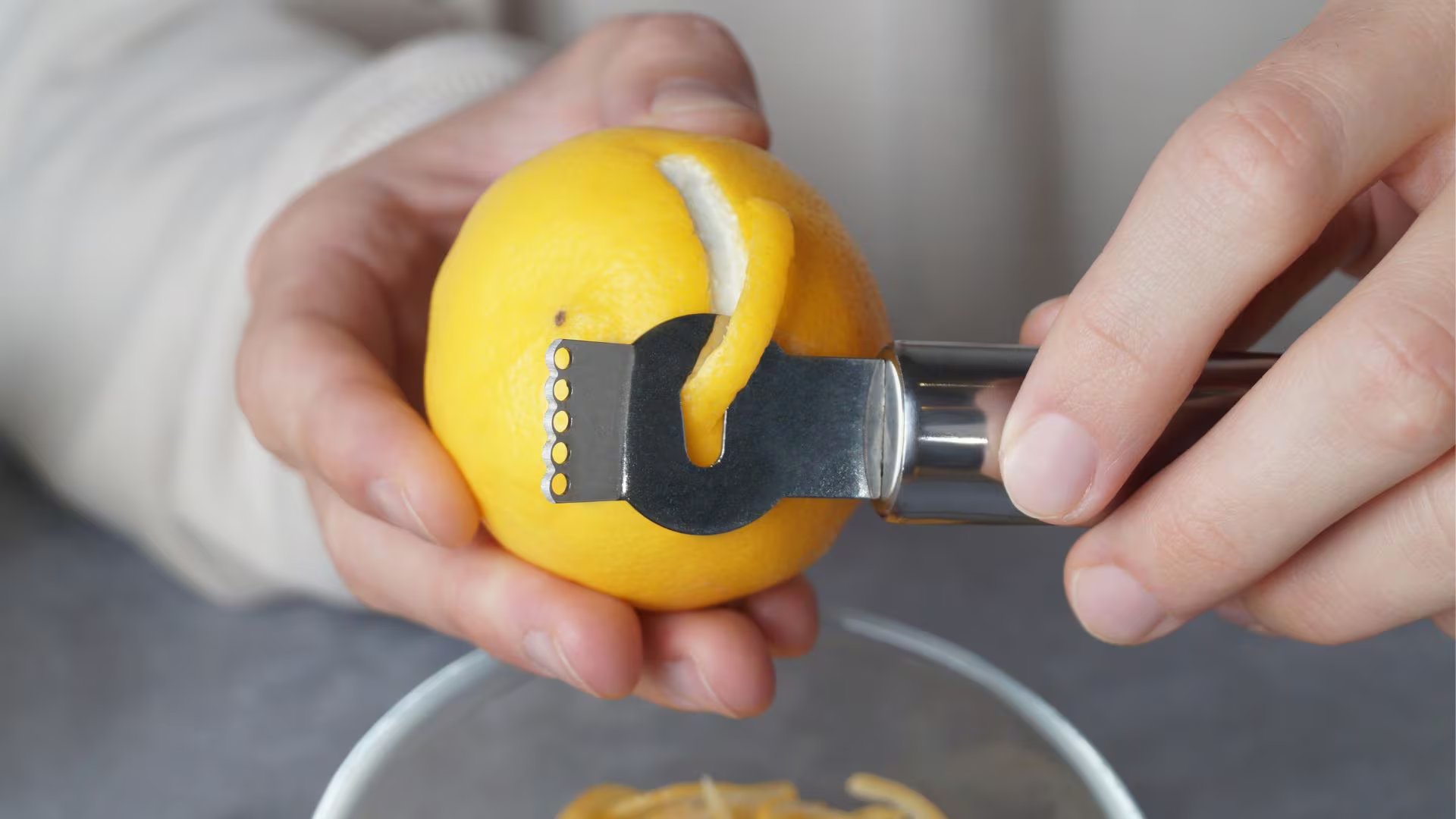 Un hombre pela un limón antes de cocinar con él (Canva)
