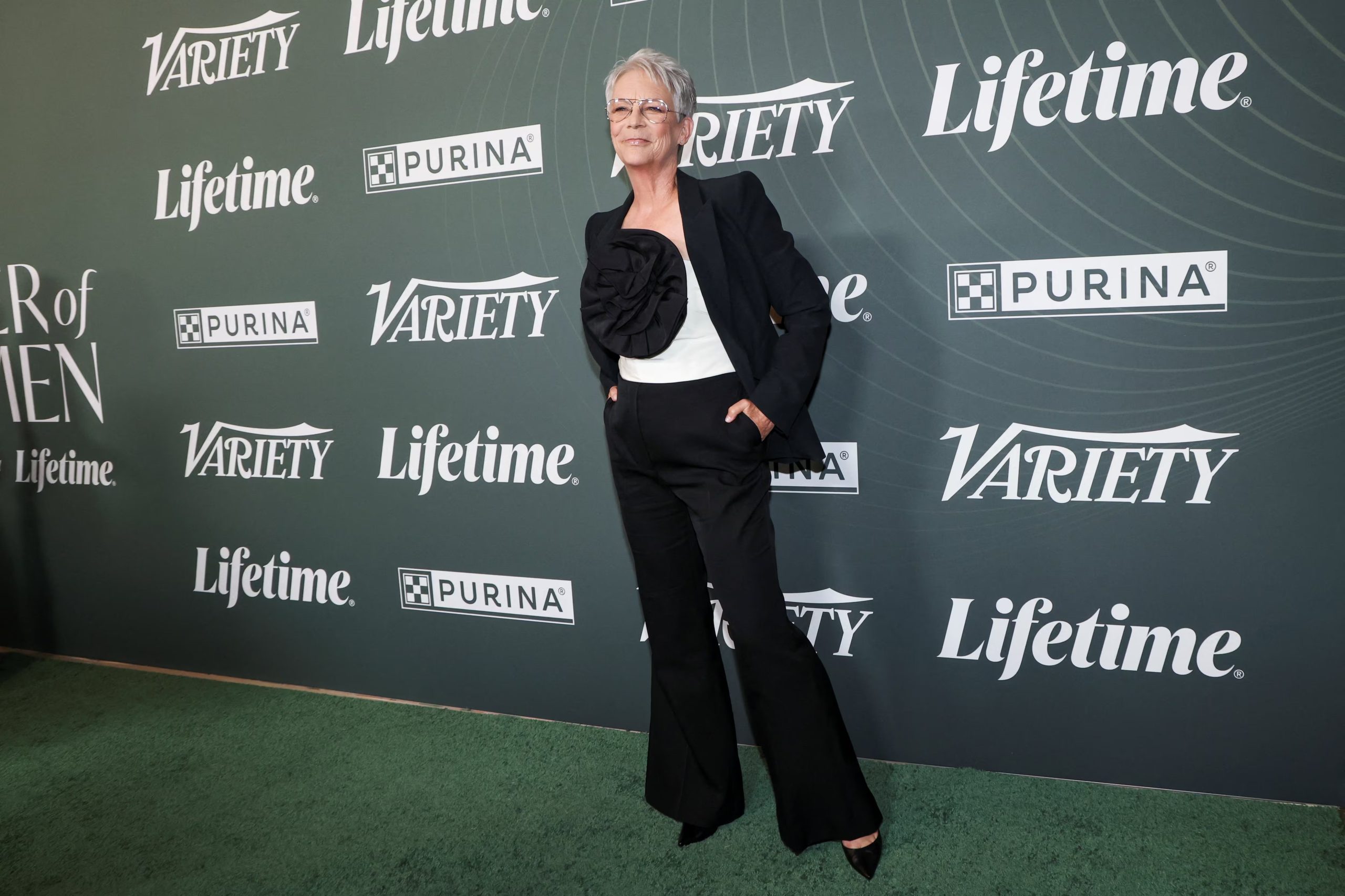 El pantalón negro con caída estructurada y blusa blanca decorada demuestra la elegancia sobria y moderna de Jamie Lee Curtis en la alfombra verde (REUTERS/Mario Anzuoni)