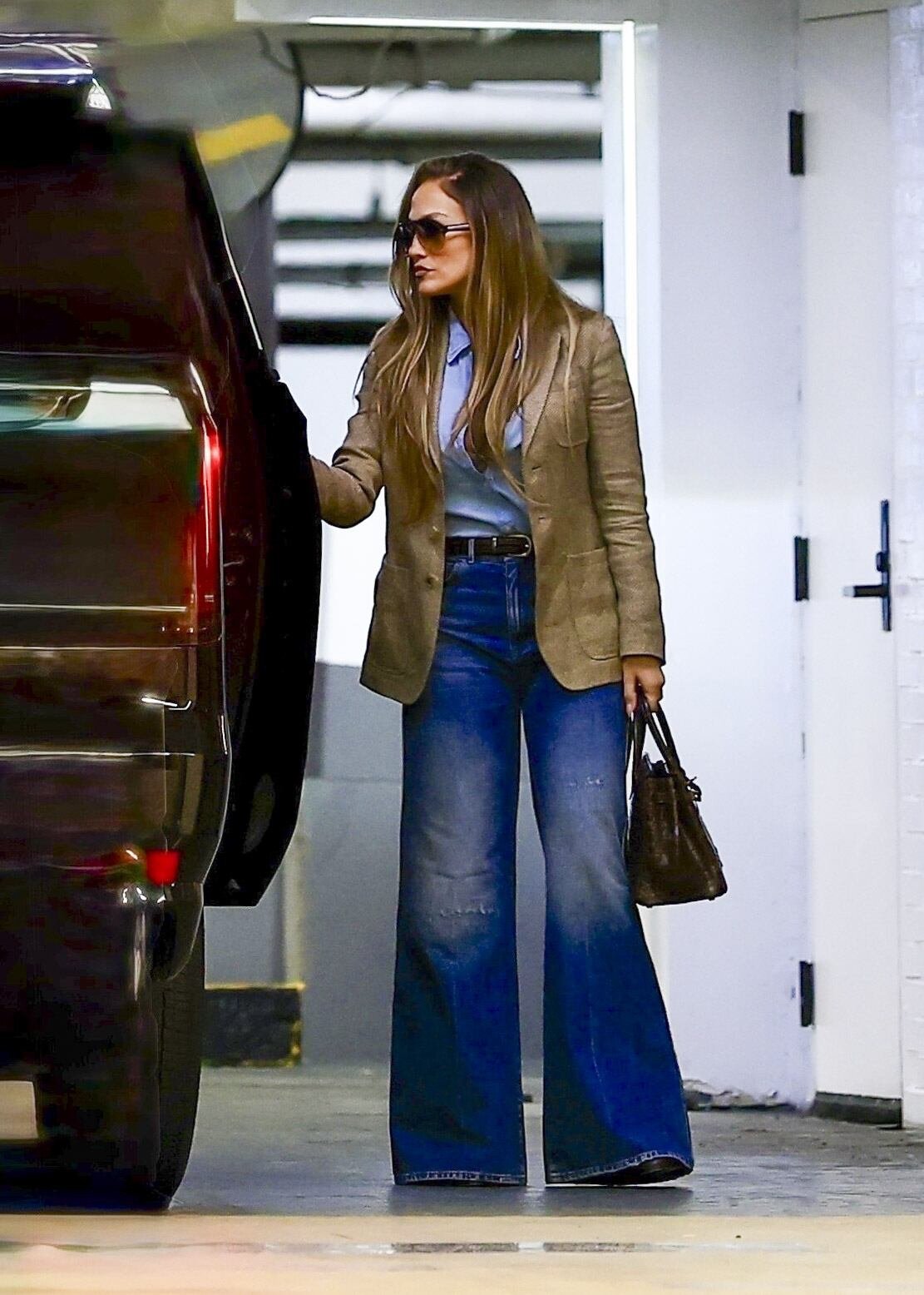 El vaquero acampanado de lavado oscuro y cintura alta evoca la moda setentera, mientras Jennifer Lopez reinventa la silueta con toques sofisticados y actuales (Backgrid/The Grosby Group)