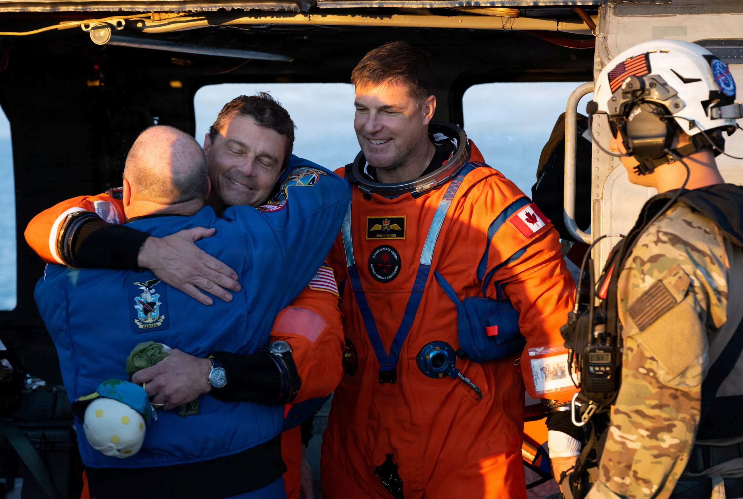 Reid Wiseman abraza a Scott Tingle, jefe de la Oficina de Astronautas de la NASA, mientras el astronauta de la Agencia Espacial Canadiense (CSA), Jeremy Hansen, se encuentra a su lado (NASA, REUTERS)