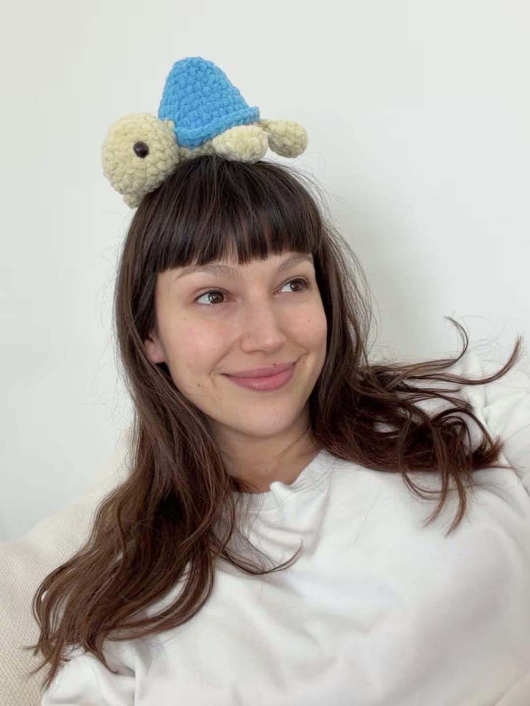 Úrsula posa sonriente con una tortuga de peluche en la cabeza