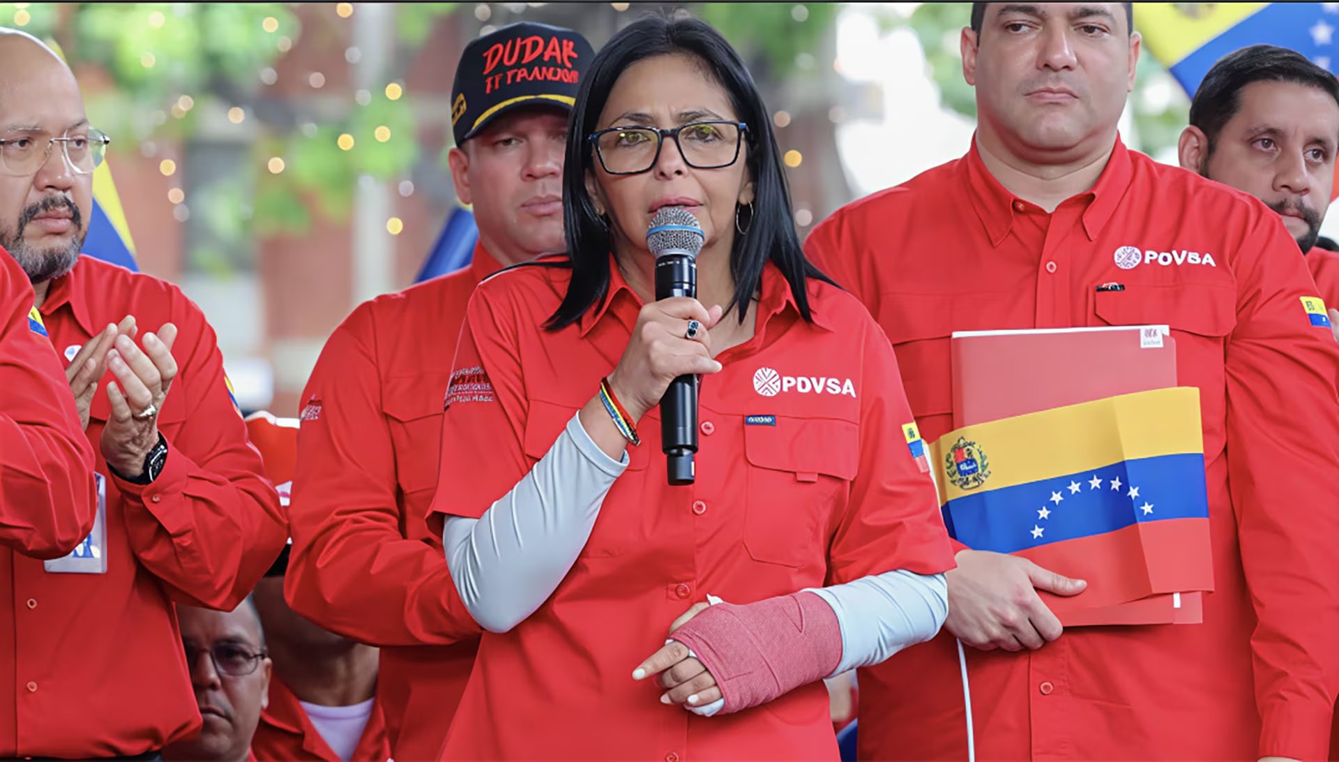 La Vicepresidenta Ejecutiva de Venezuela, Delcy Rodríguez, se dirige a la multitud con un micrófono en un acto público, luciendo una camisa con el logo de PDVSA