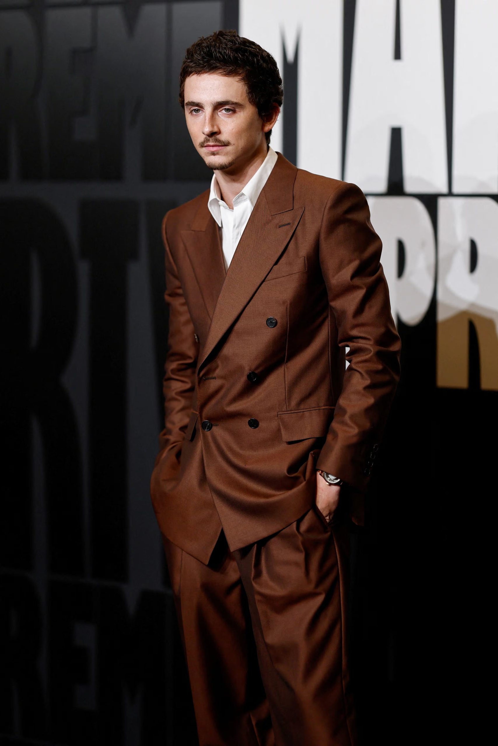 El traje marrón satinado de corte amplio y camisa blanca sin corbata reflejó la preferencia de Timothée Chalamet por el estilo relajado y contemporáneo en alfombras rojas (REUTERS/Benoit Tessier)