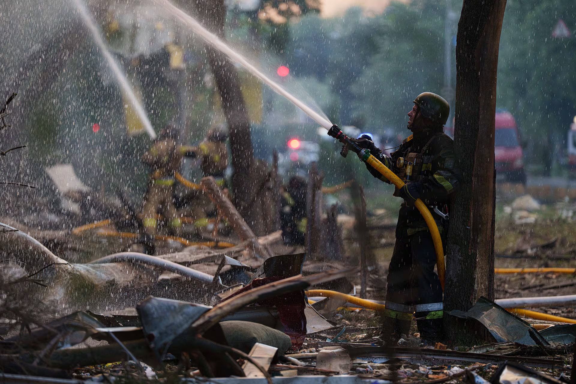 Un bombero rocía agua entre los escombros para extinguir un incendio en Ucrania, después del mayor ataque ruso con misiles del año.