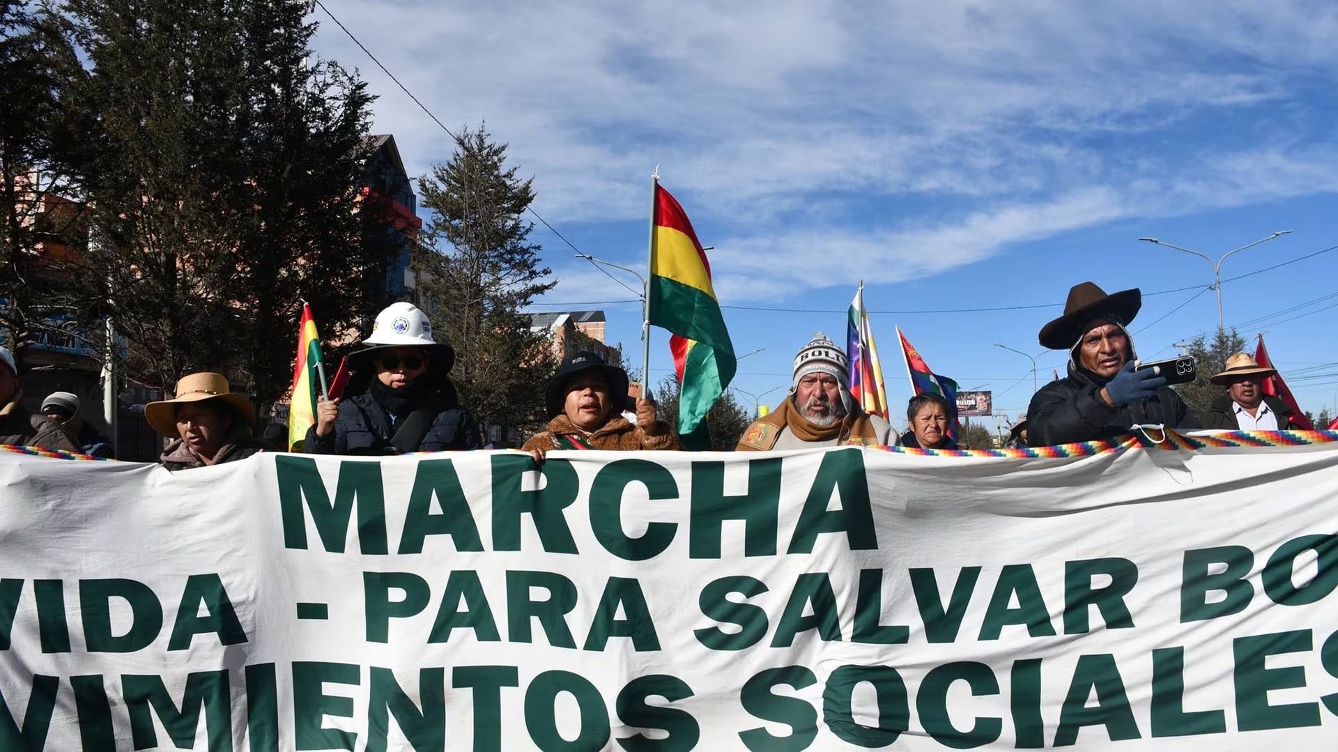Seguidores de Evo Morales sostienen una pancarta y banderas bolivianas mientras marchan hacia La Paz para protestar contra el Gobierno.
