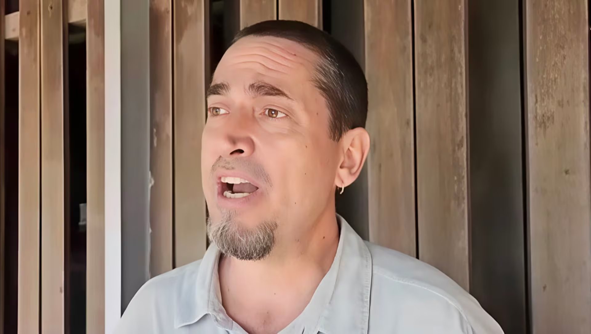 El sociólogo Antonio González Plesmann, del colectivo de derechos humanos Surgentes, se expresa con determinación frente a un fondo de listones de madera.