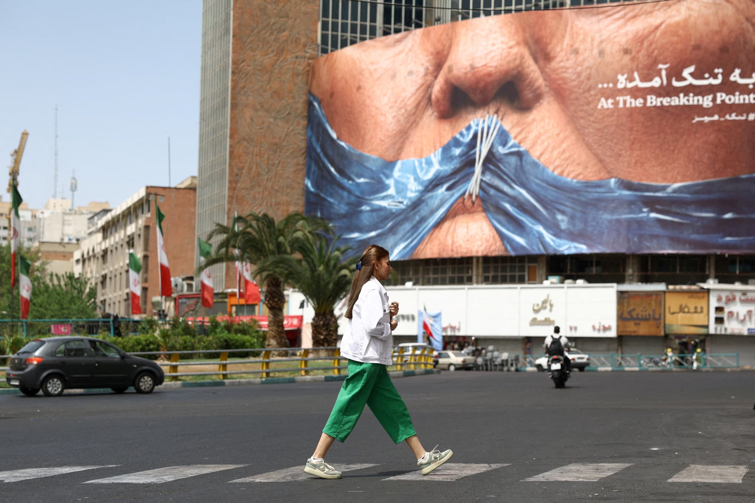 Una mujer pasa junto a una valla publicitaria contra Estados Unidos que representa al presidente estadounidense Donald Trump y el estrecho de Ormuz, en Teherán, Irán, 8 de mayo de 2026 (Majid Asgaripour/REUTERS)