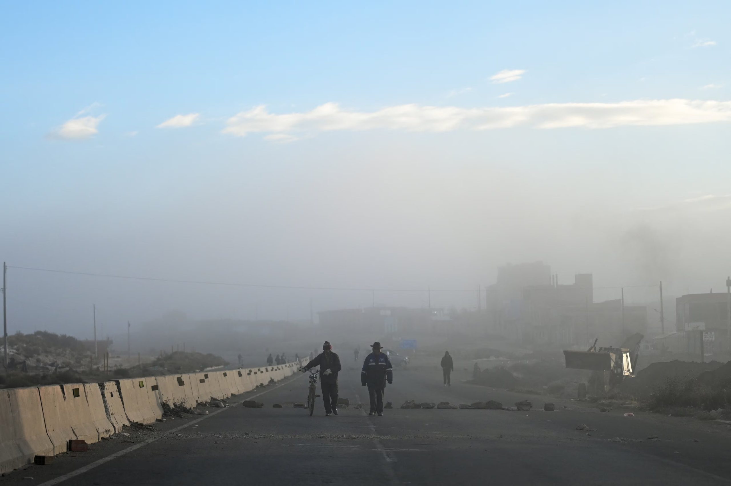 Dos personas caminan en medio de una carretera bloqueada en la localidad de Apacheta, en el altiplano boliviano. 13 de mayo de 2026 (REUTERS/ Claudia Morales)