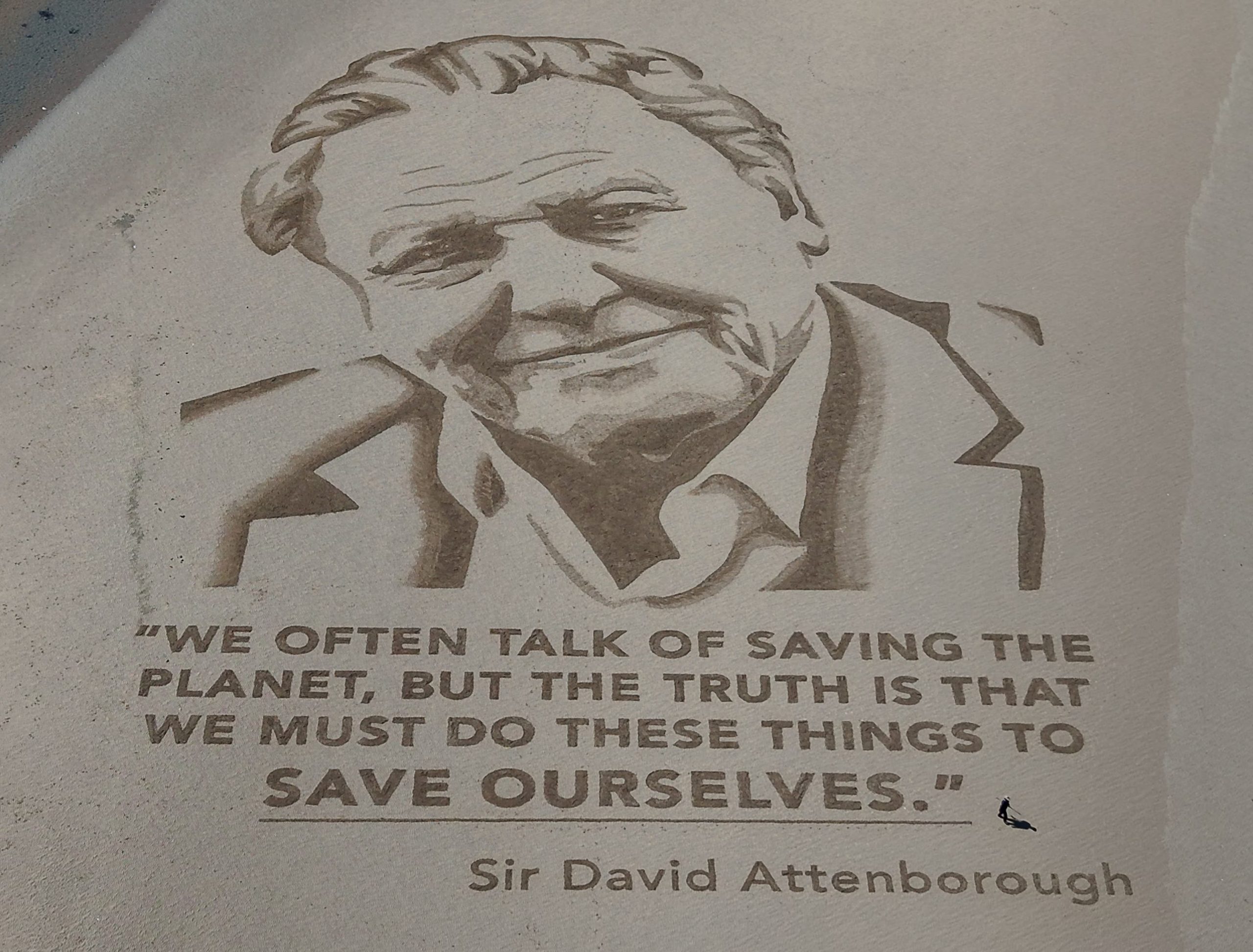 Una imagen tomada con un dron muestra a un artista del equipo artístico Sand In Your Eye dando los últimos retoques a un retrato gigante de David Attenborough hecho de arena para conmemorar el centenario del conservacionista, en la playa de Morecambe, Gran Bretaña, el 6 de mayo de 2026. REUTERS/Phil Noble