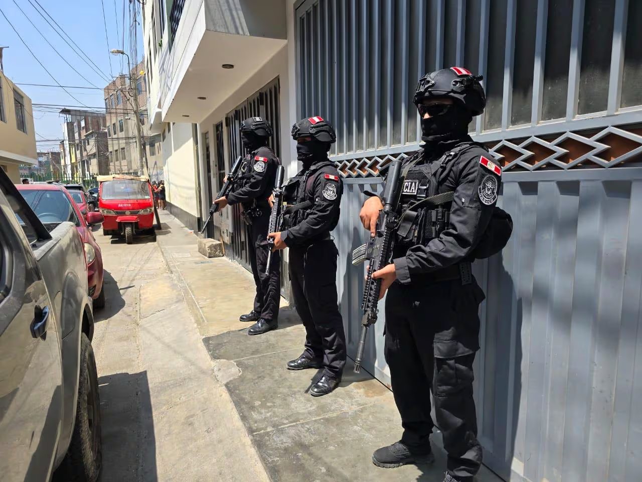 Unos tres agentes de una división policial especializada contra el crimen organizado custodian los exteriores de una vivienda intervenida en Lima. (Mininter)