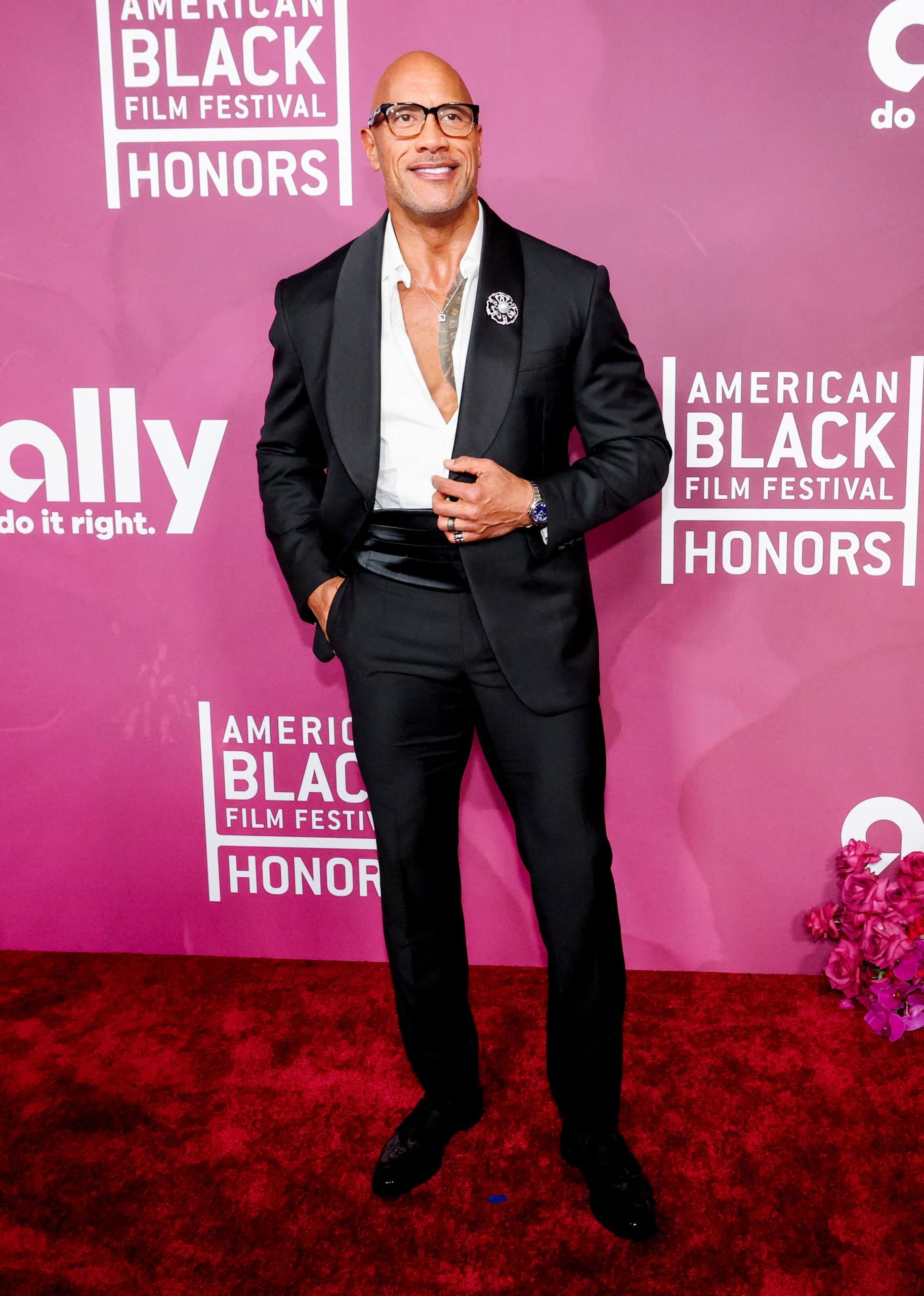 En la alfombra roja, el esmoquin negro satinado y los detalles plateados demuestran el dominio de Dwayne Johnson en la gala contemporánea (REUTERS/Mario Anzuoni)