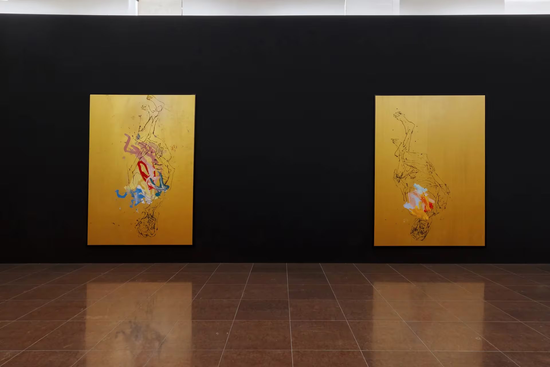 Dos cuadros del renombrado artista Georg Baselitz, caracterizados por figuras invertidas y toques de color sobre fondos dorados, se exhiben en una pared negra en una galería de arte. (Celestia Studio)