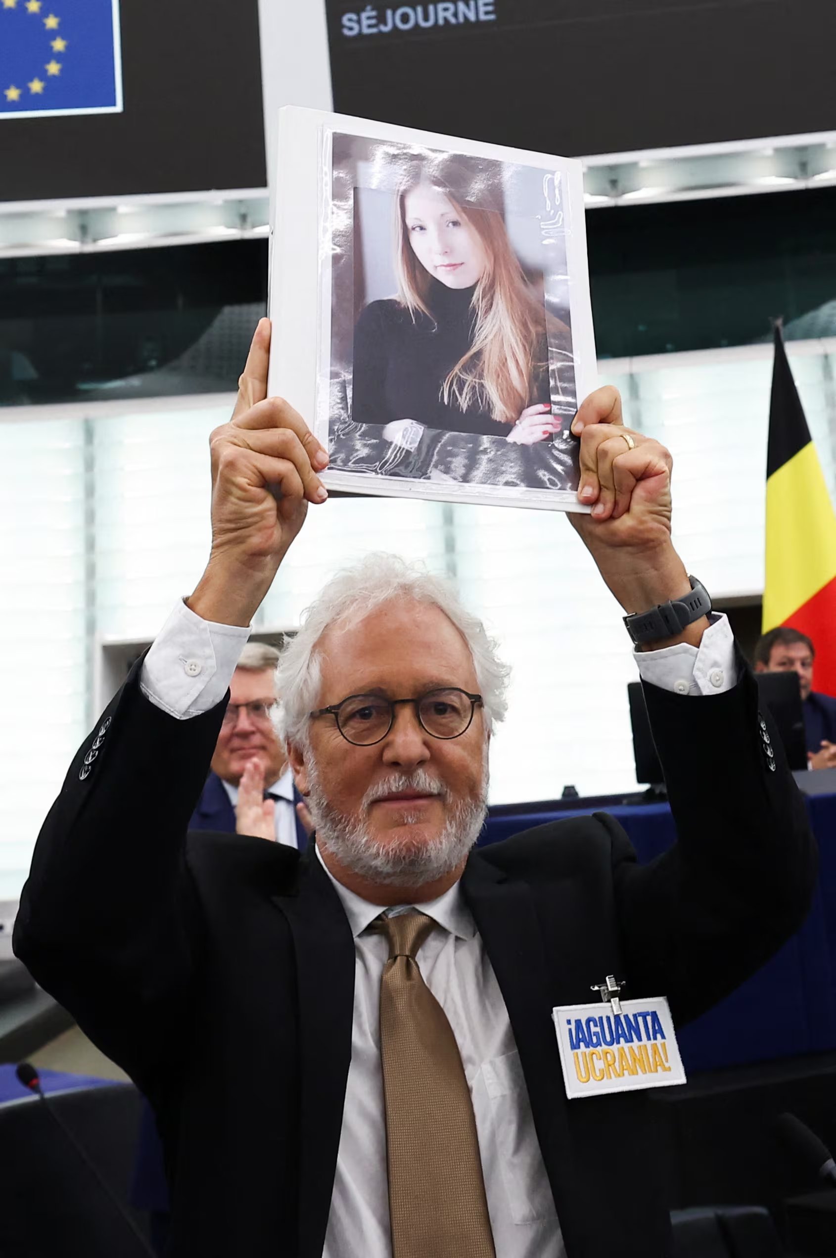 Héctor Abad Faciolince levanta en septiembre del 2023 en el Parlamento europeo una foto de la escritora ucraniana Victoria Amelina, muerta luego de un ataque ruso con misiles en junio de ese año. Abad sobrevivió al ataque. (REUTERS/Yves Herman)