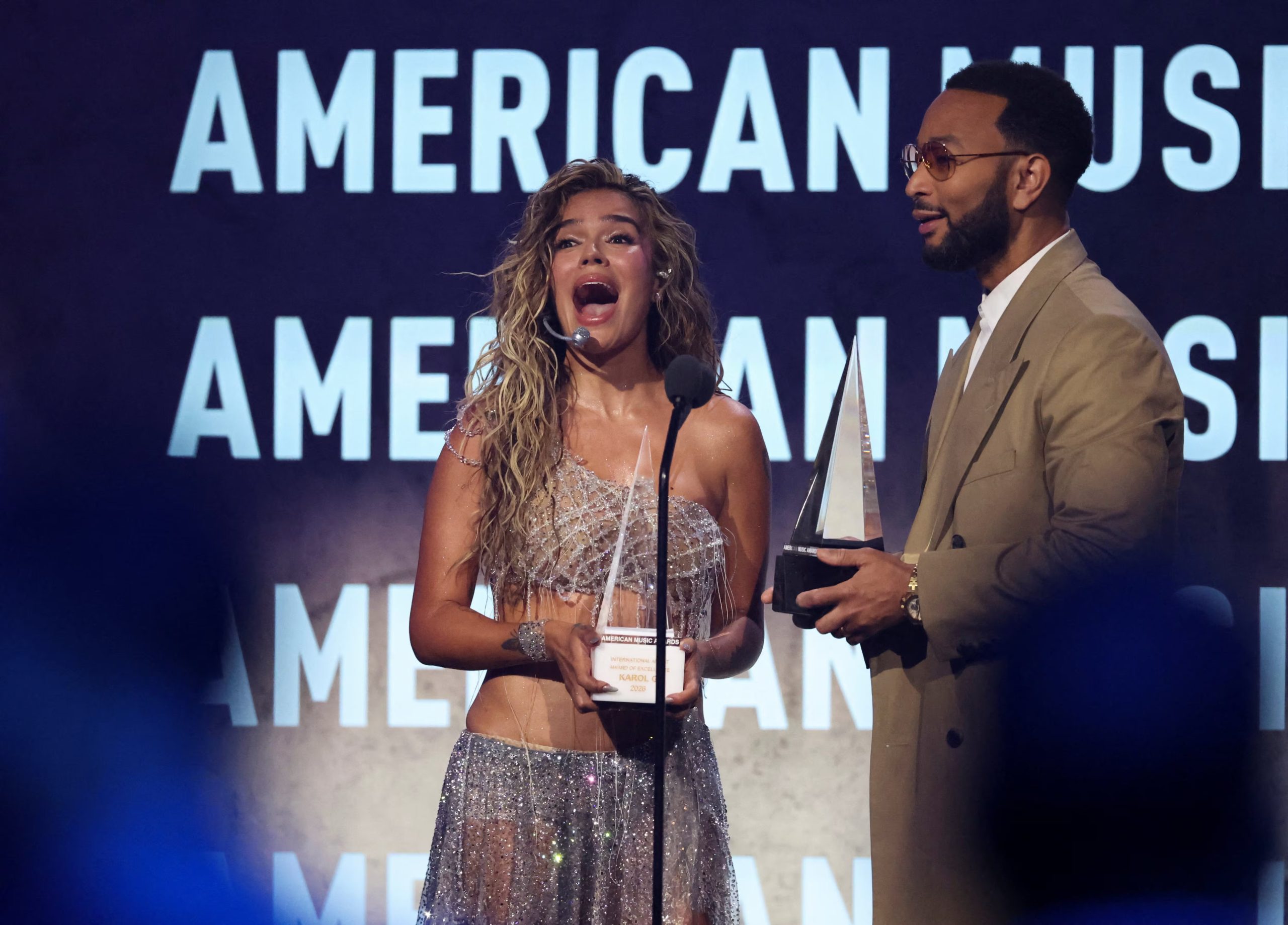 Momento en el que Karol G recibe su segundo galardón de manos de John Legend - crédito REUTERS/Mario Anzuoni