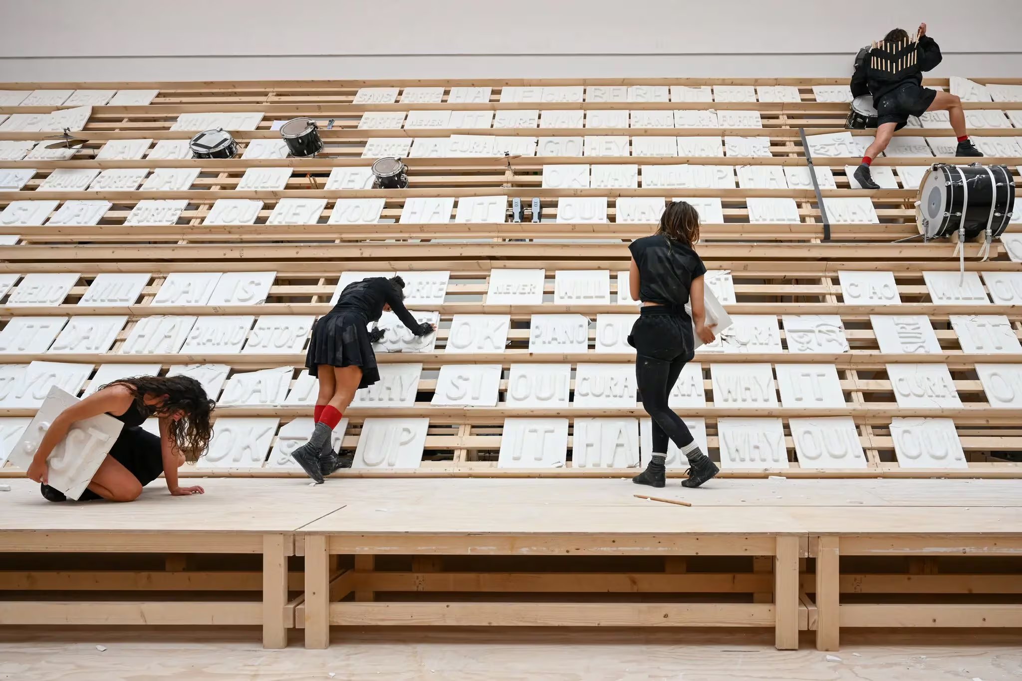 En el pabellón, los artistas se mueven rápidamente de arriba abajo sobre estantes de madera que sostienen tablillas de yeso con palabras en varios idiomas grabadas en ellas (Crédito: Casey Kelbaugh para The New York Times)