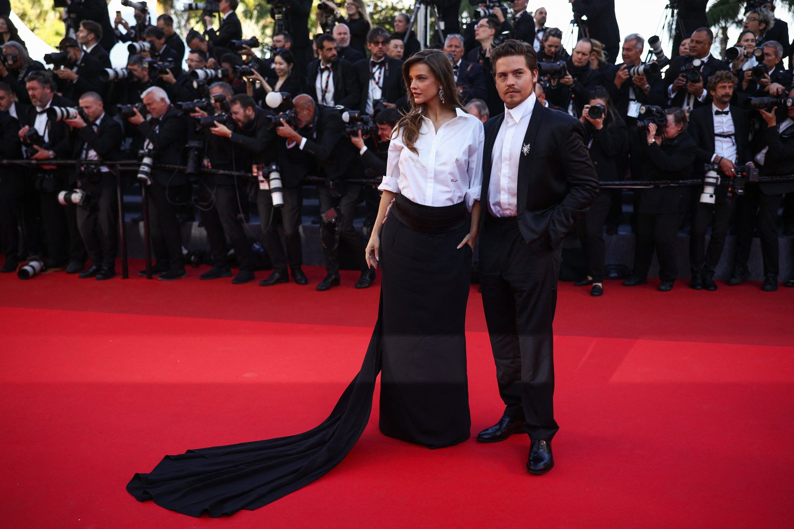 Barbara Palvin y Dylan Sprouse combinan camisa blanca de popelín y traje negro con detalles vanguardistas, logrando un contraste sofisticado y fresco en la alfombra roja REUTERS/Marko Djurica