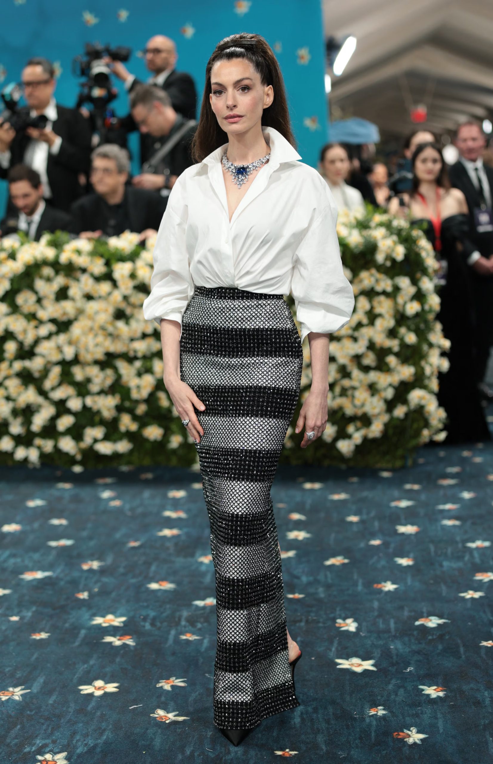 La camisa blanca de escote amplio y mangas remangadas de Anne Hathaway muestra cómo pequeños gestos estilísticos pueden transformar una prenda básica en un ícono de vanguardia (REUTERS/Mario Anzuoni)