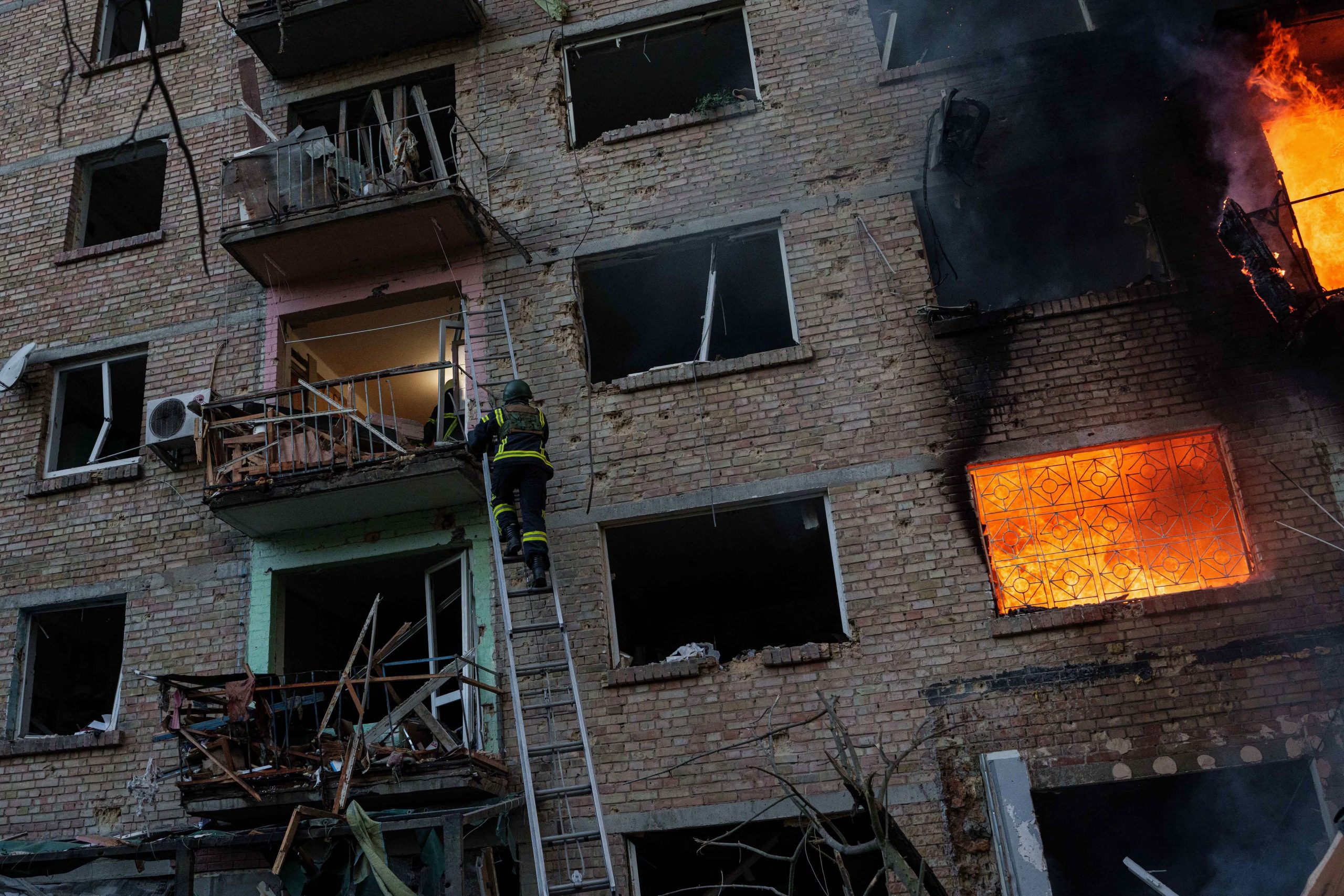 Un rescatista sube por una escalera para ayudar a evacuar a las personas de un edificio residencial que está siendo destruido tras un ataque ruso en Kiev.