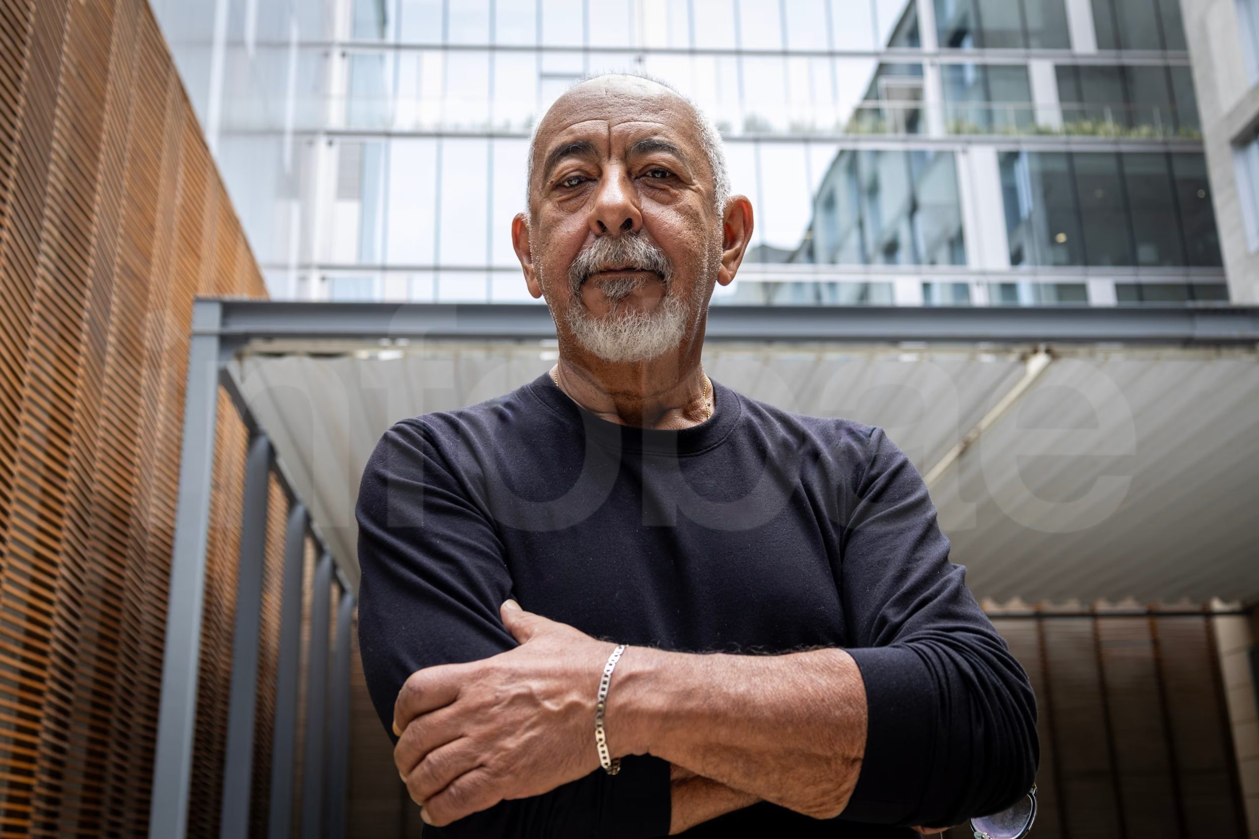 El reconocido escritor cubano Leonardo Padura posa con los brazos cruzados frente a un edificio moderno. (Paula Elizalde)