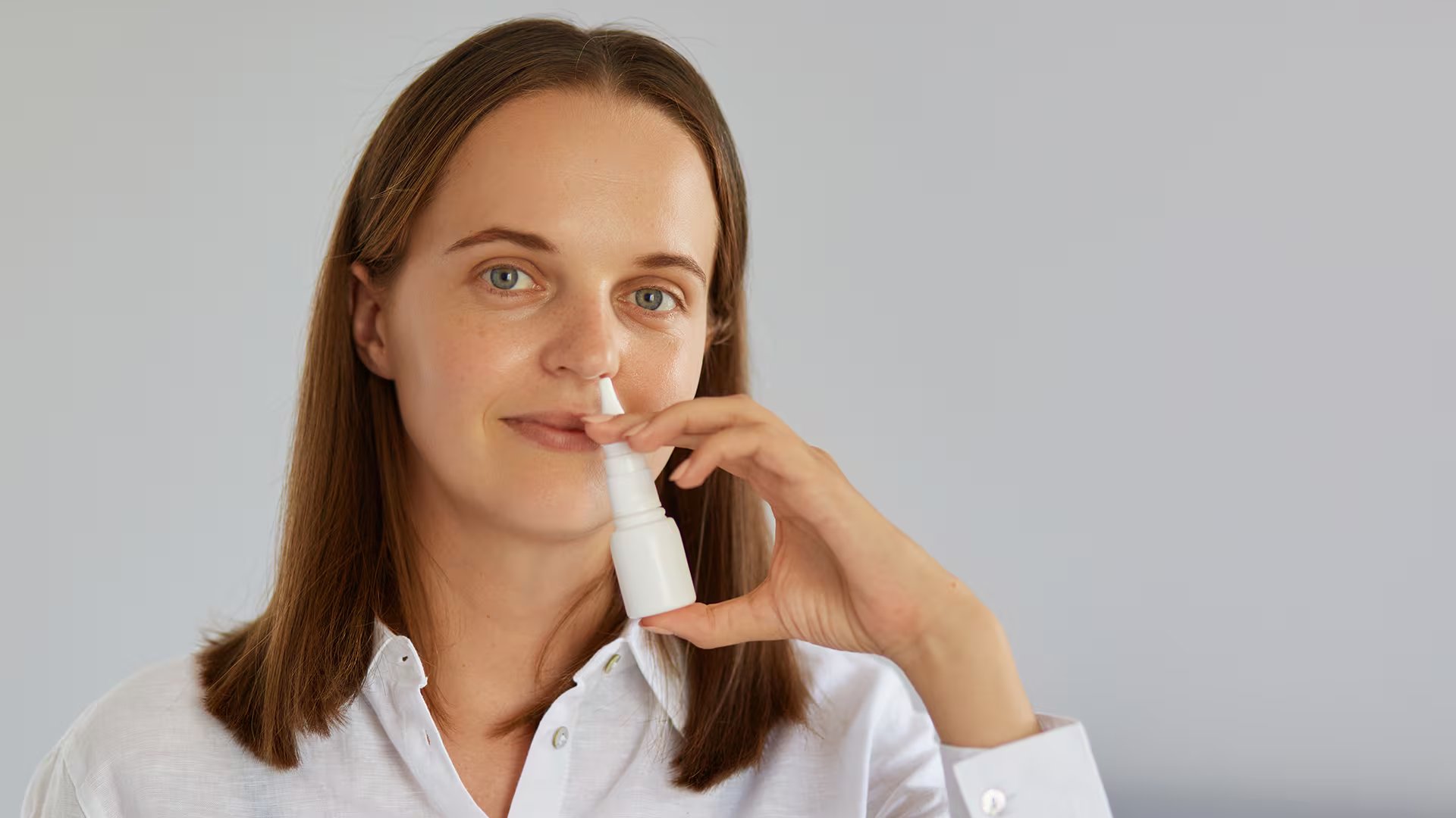 Una mujer aplica un spray nasal para aliviar los síntomas de la rinitis alérgica. (Freepik)