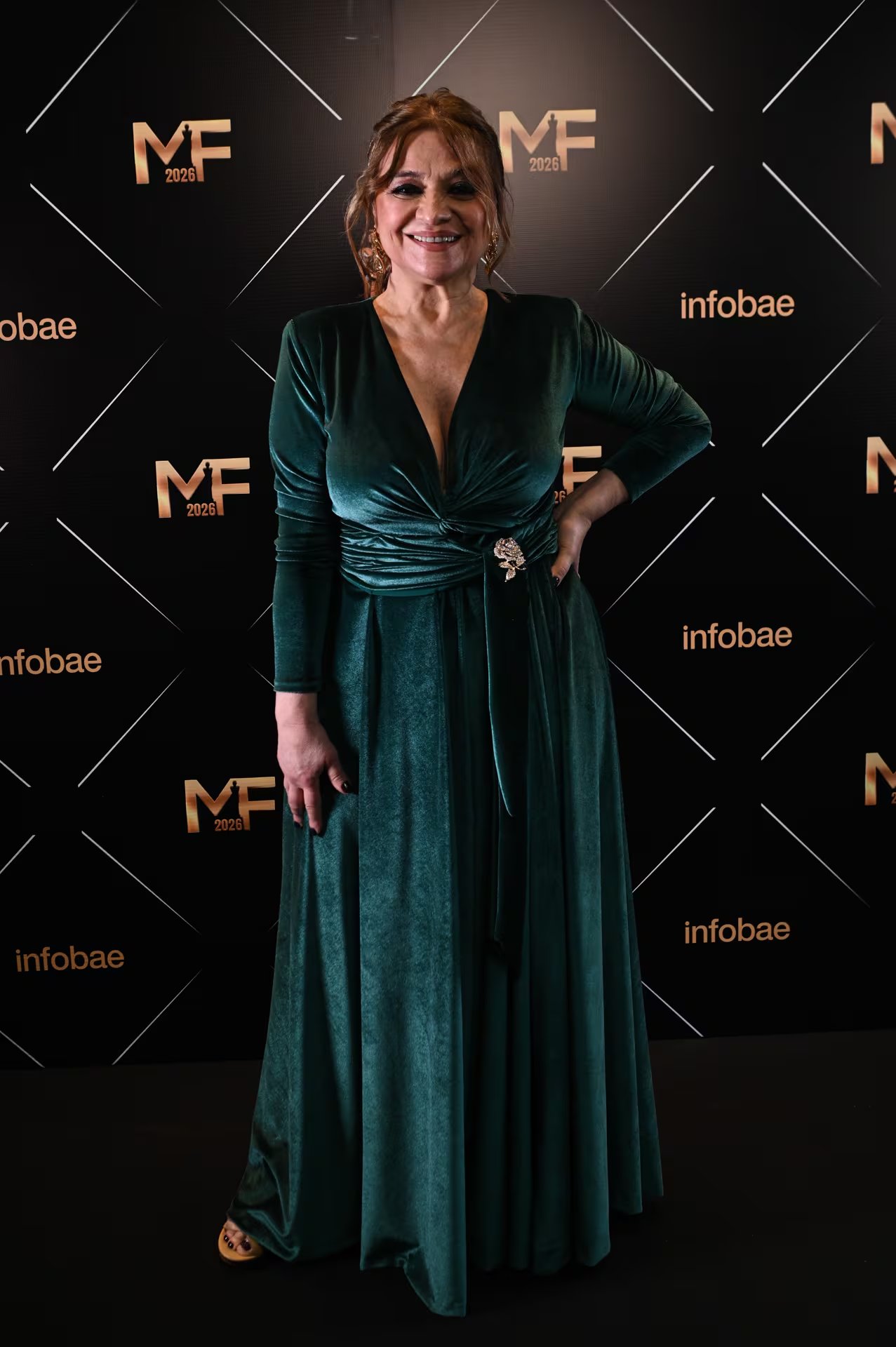 Marcela Feudale se inclinó por un vestido largo de terciopelo verde con escote en V y mangas largas. El diseño se destaca por un drapeado en la cintura, rematado con un broche decorativo